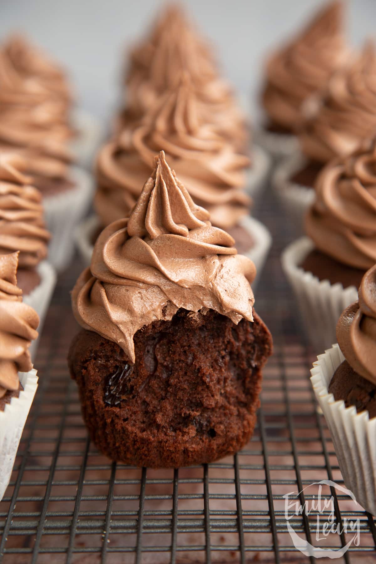 Chocolate raisin muffins on a wire rack. The muffin in the fore is unwrapped with a bite out of it. 