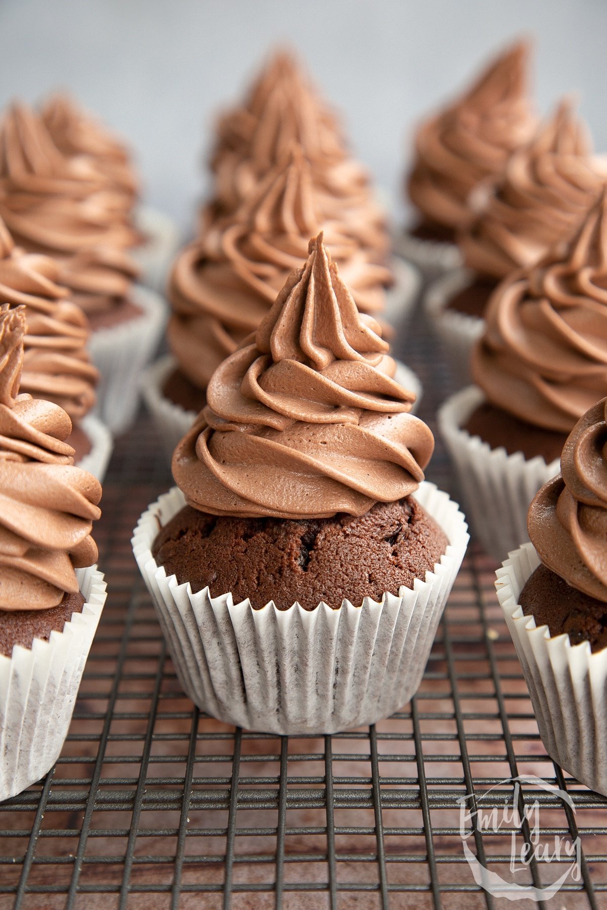 Freshly frosted chocolate raisin muffins on a cooling rack.