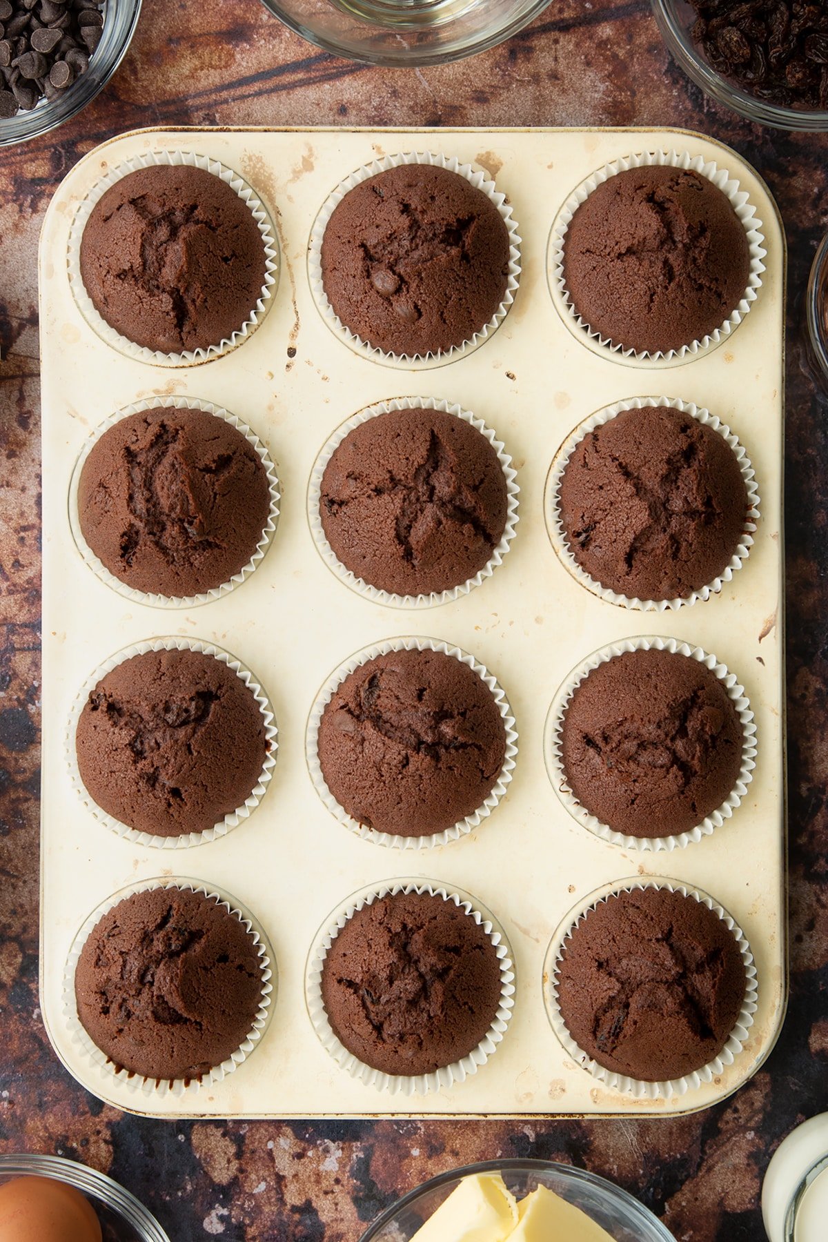 Freshly baked chocolate raisin muffins in a tray.