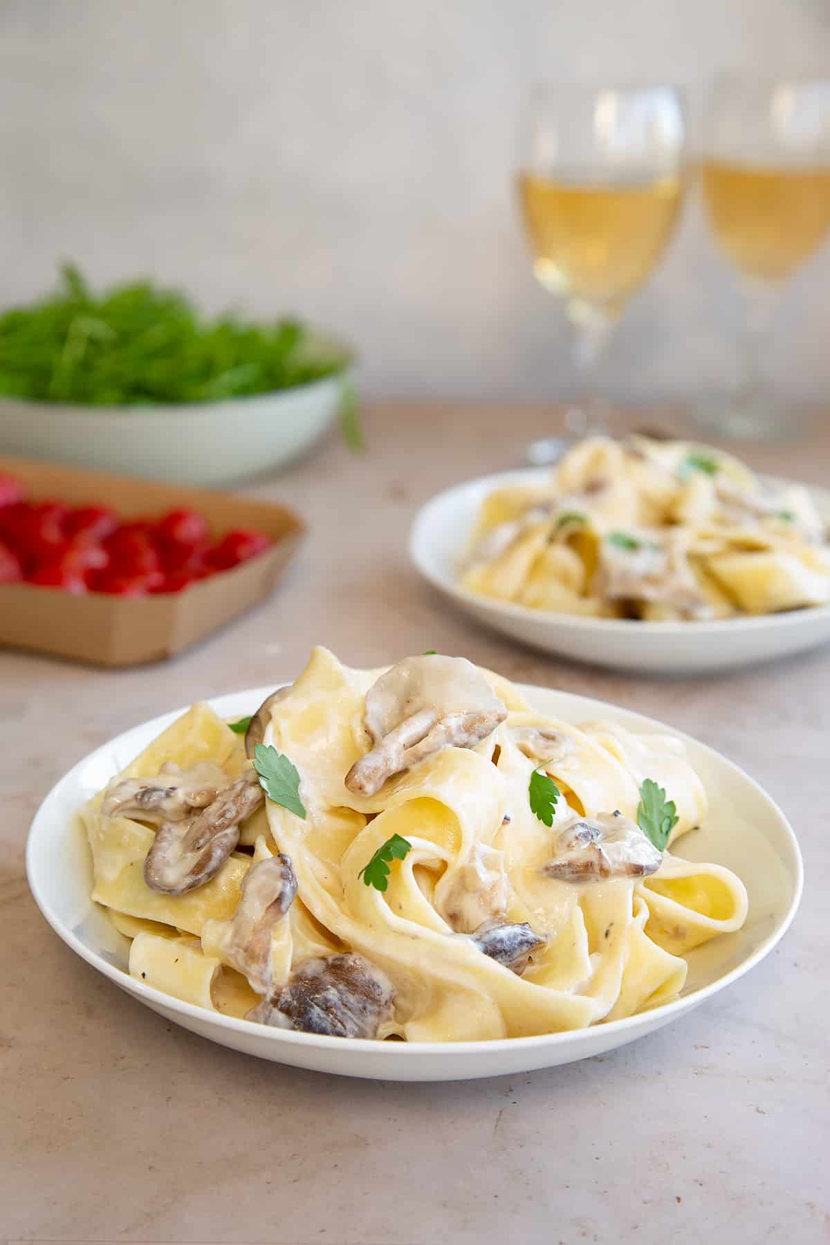 side view of Creamy mushroom pappardelle topped with parsley in a white pasta bowl.