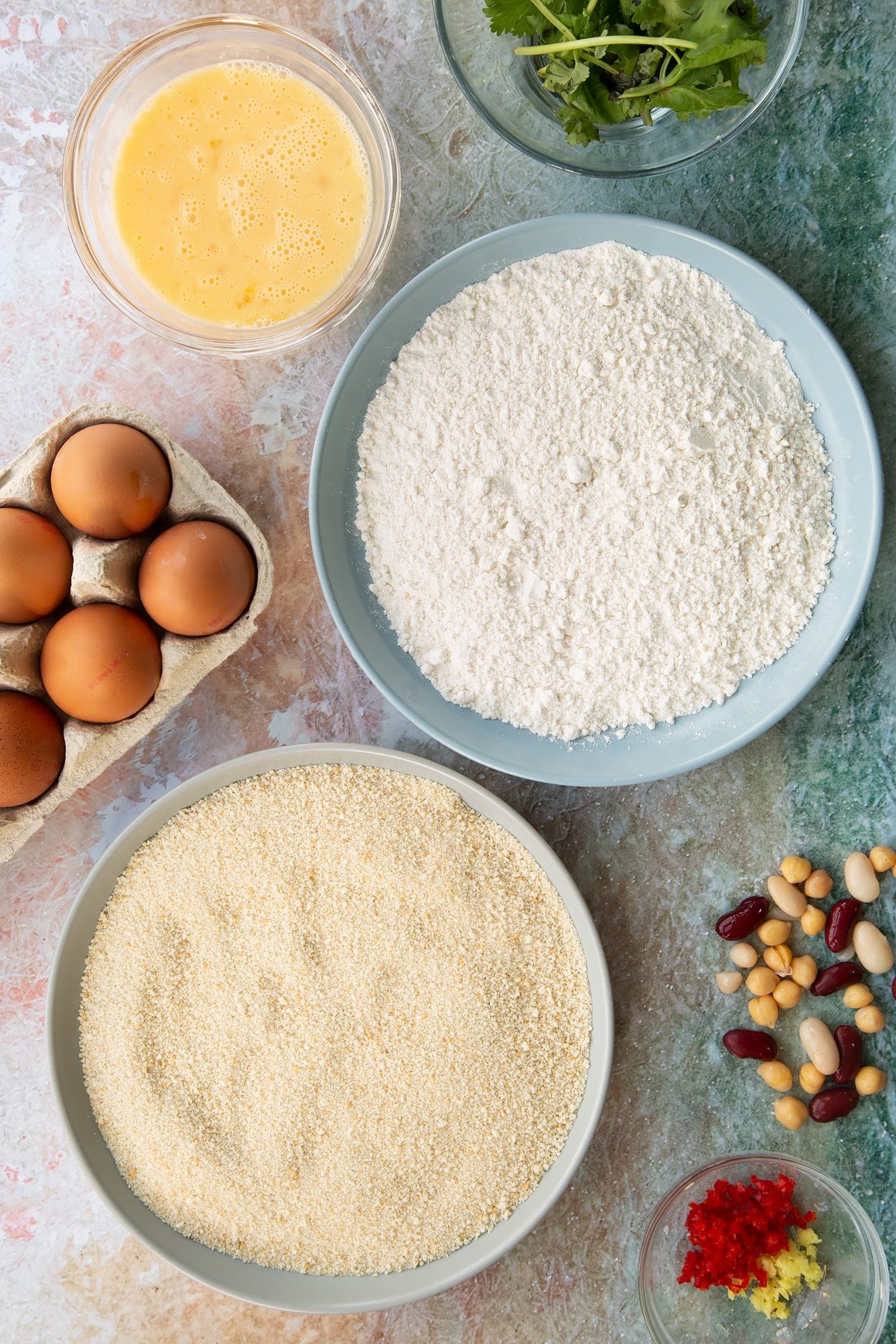 3 dishes of butter, flour and breadcrumbs on a green background.