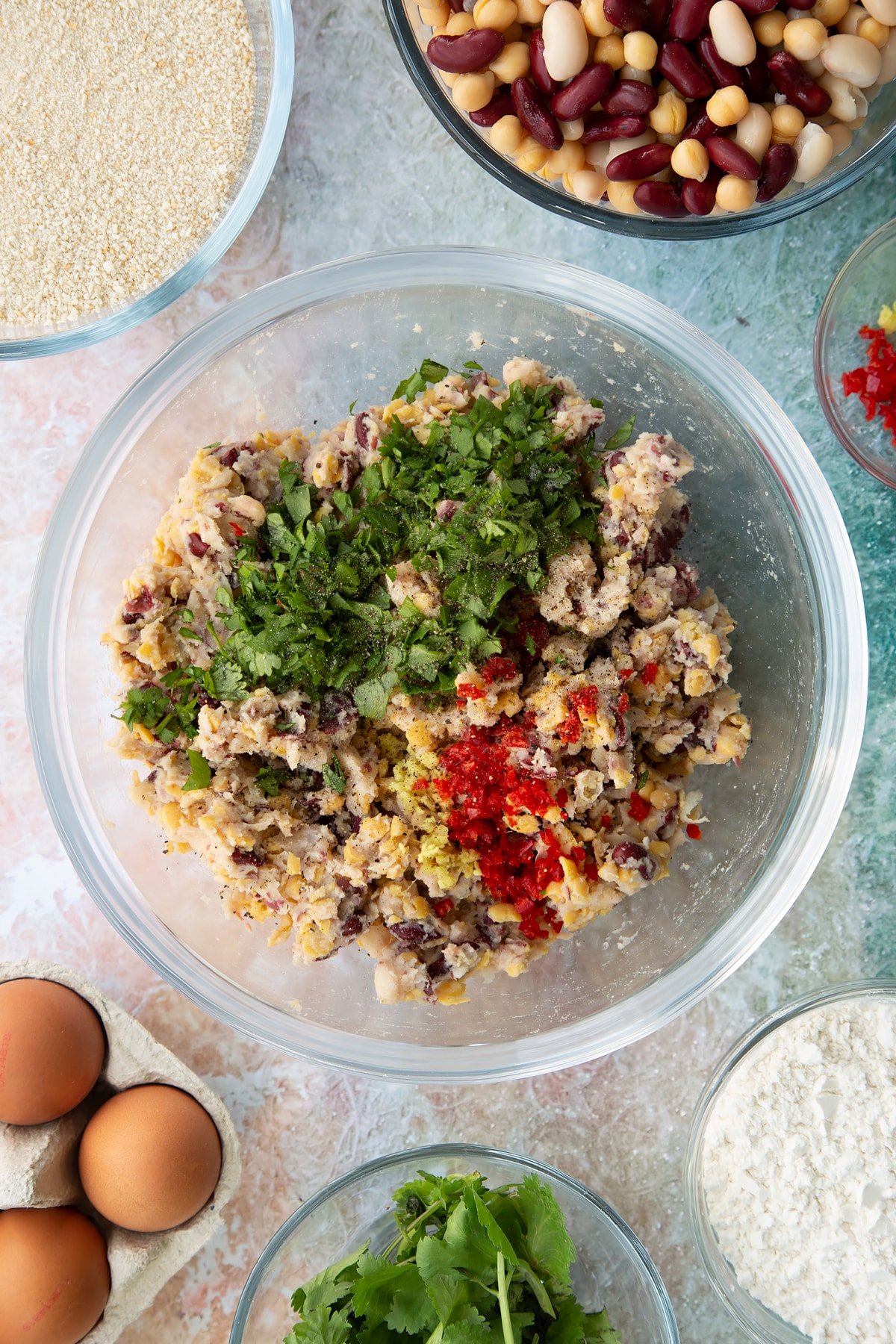 mushed canned beans and chickpeas in a large clear bowl mixed with coriander, ginger and chilli.