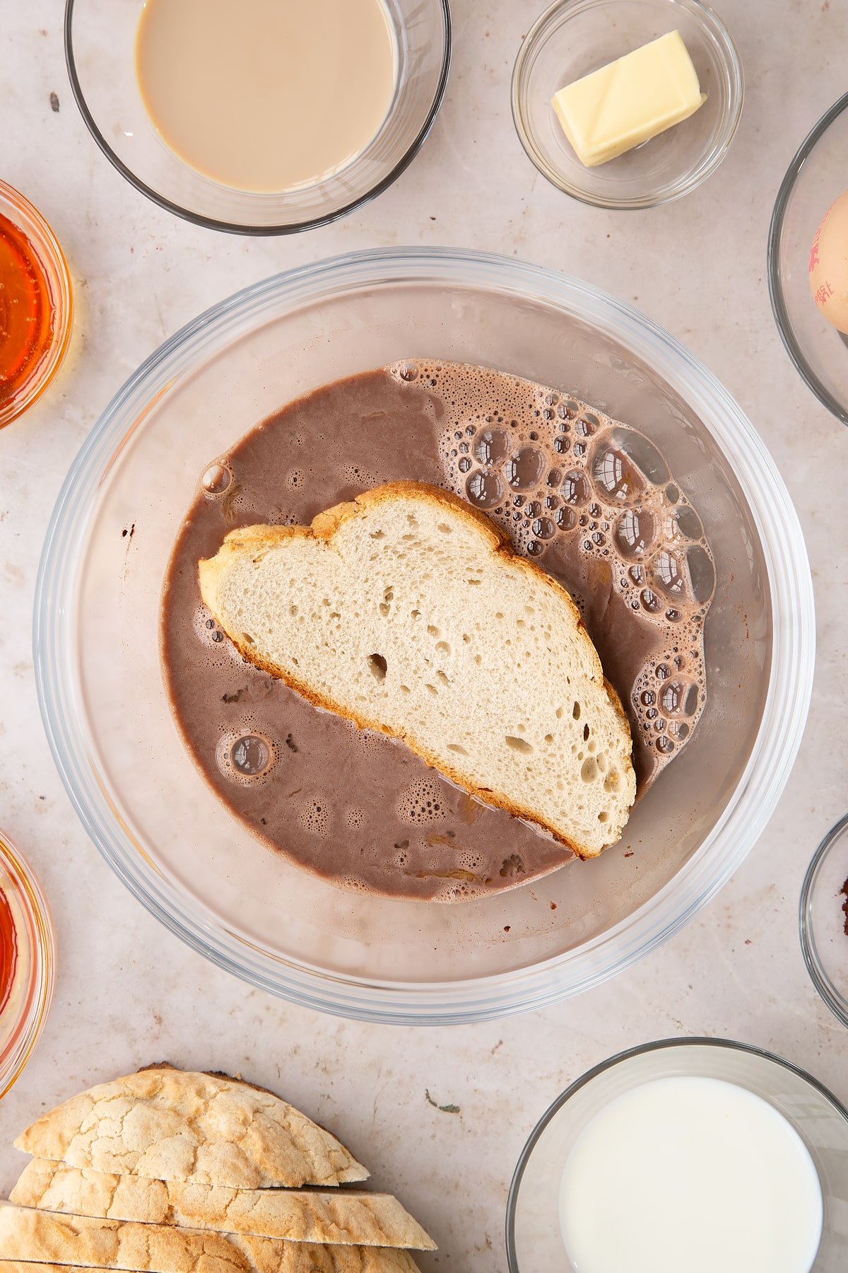 Overhead shot of slices of bread being placed into the bowl of ingredients for the Baileys French toast.