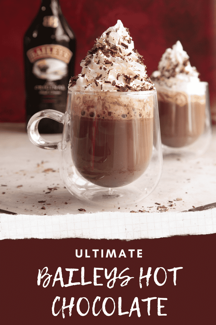 Two mugs of a rich Baileys hot chocolate recipe, topped with whipped cream and chocolate shavings. Caption reads: Ultimate Baileys hot chocolate.