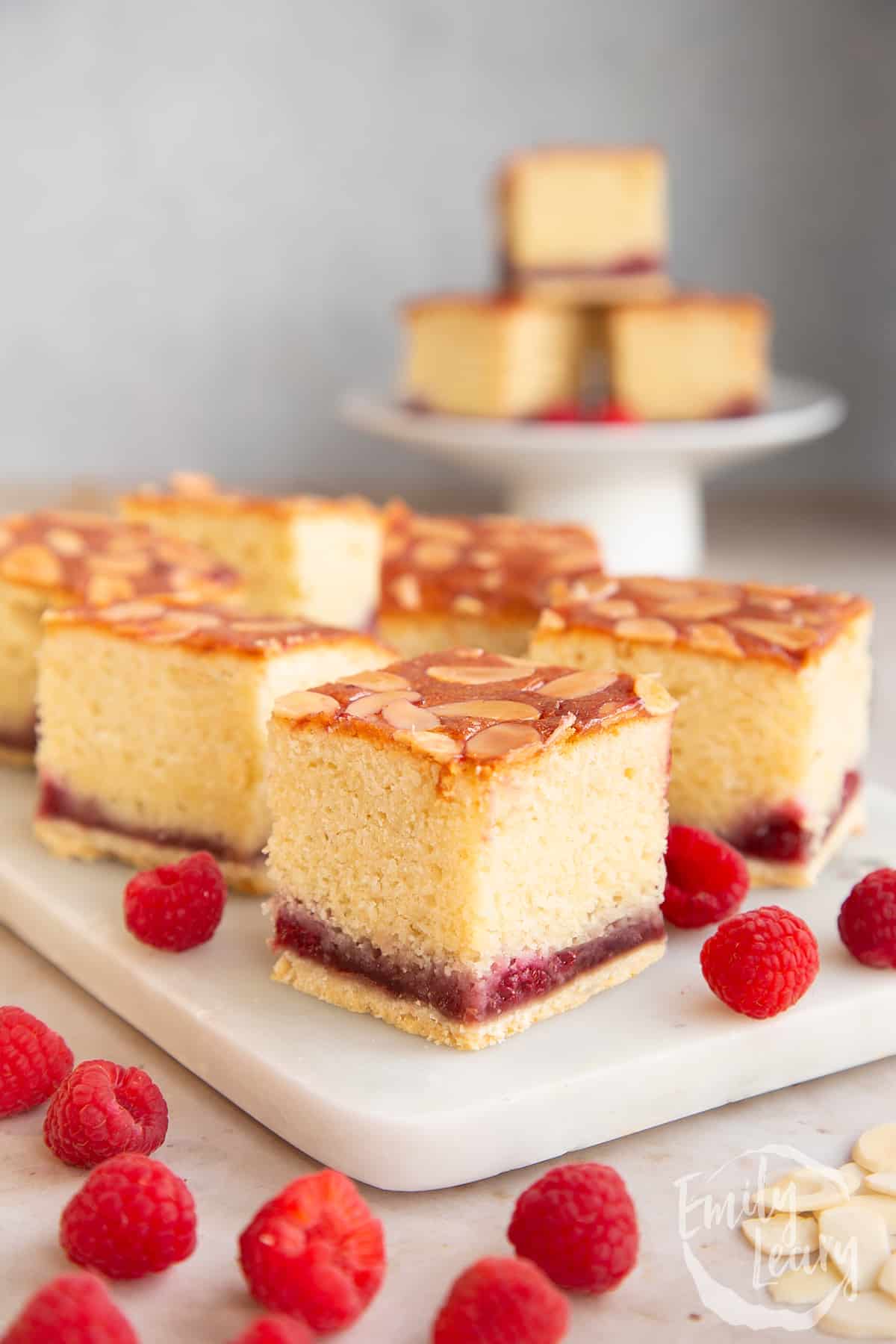 Squares of Bakewell tray bake on a white marble board.