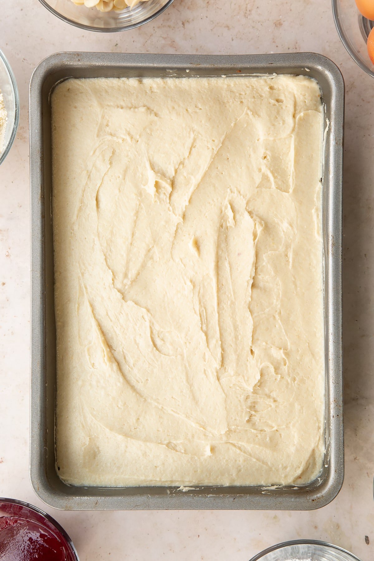 Bakewell tray bake batter in a tin, shown from above.