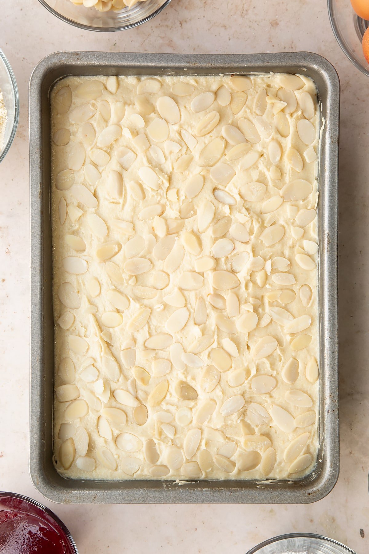 Bakewell tray bake in a tin, ready to bake, shown from above.