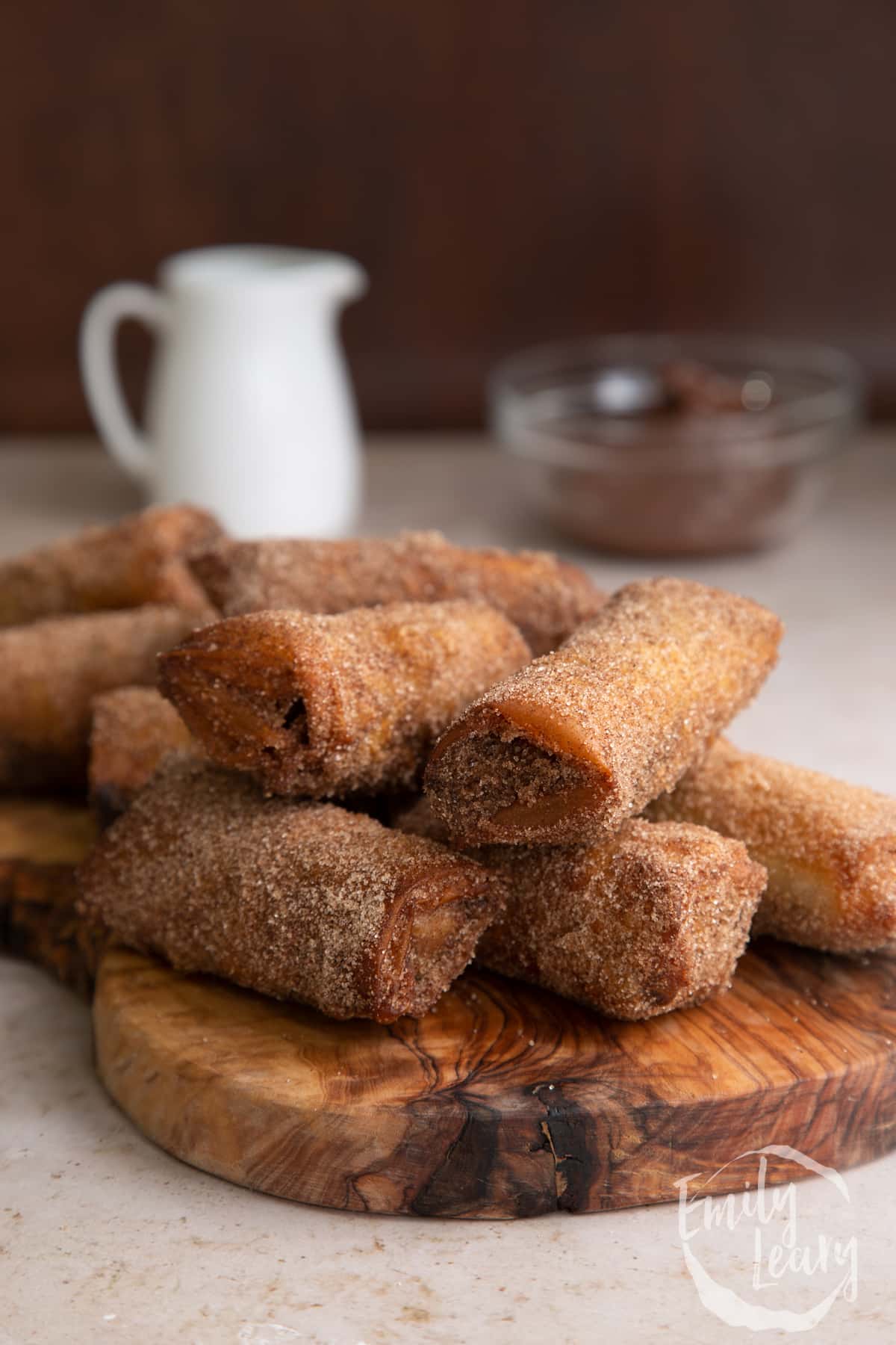 A finished stack of banana chocolate spring rolls on a wooden chopping board.