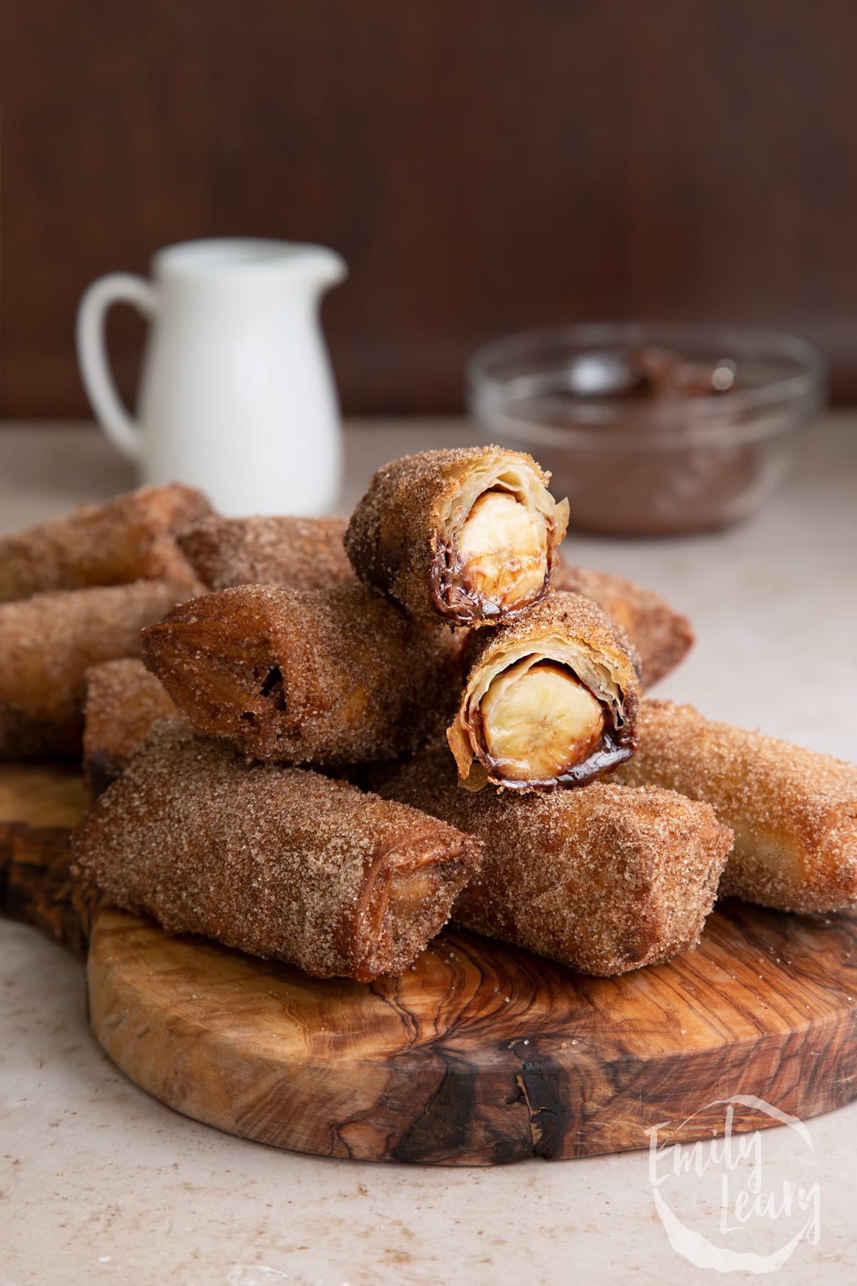 A stack of banana chocolate spring rolls with one sliced open at the top.