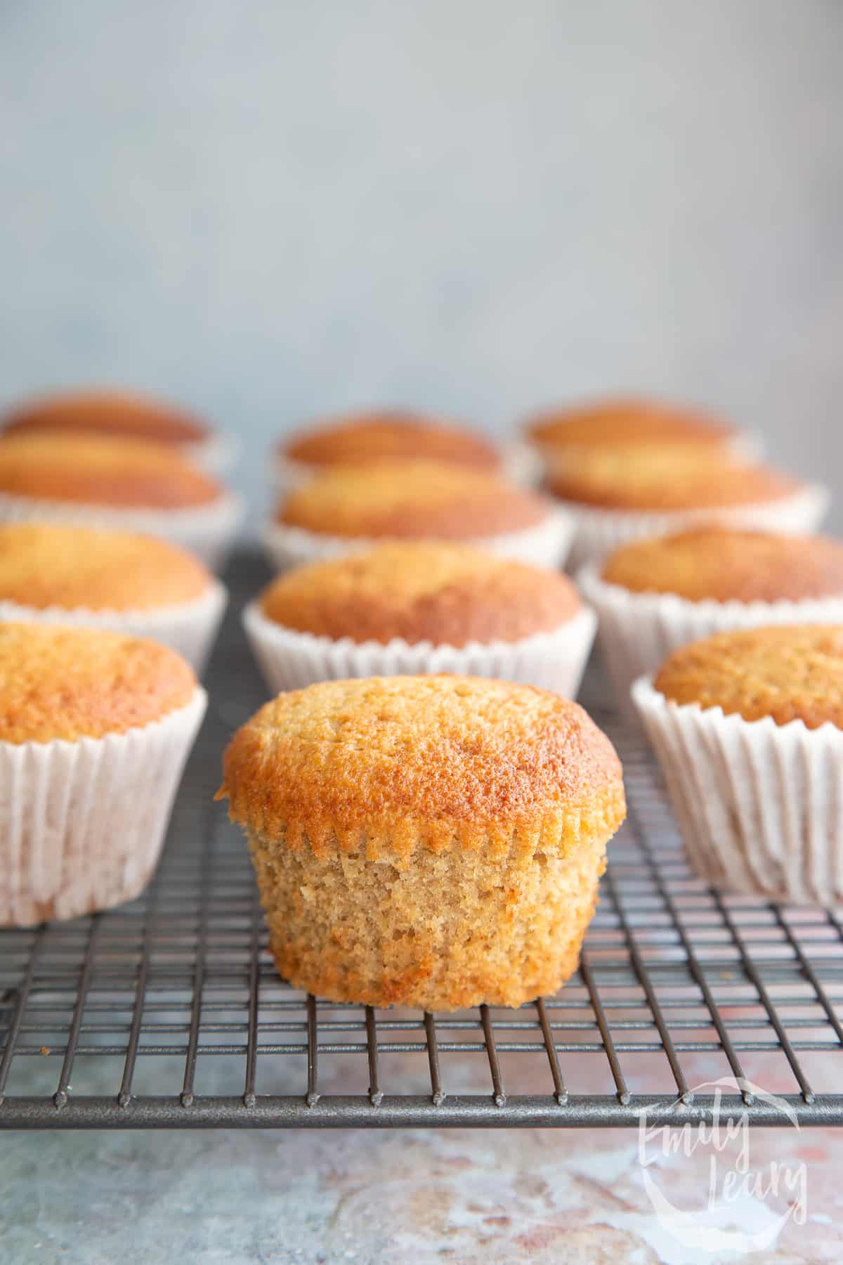 Banana cornmeal muffins on a wire rack. One has been unwrapped.