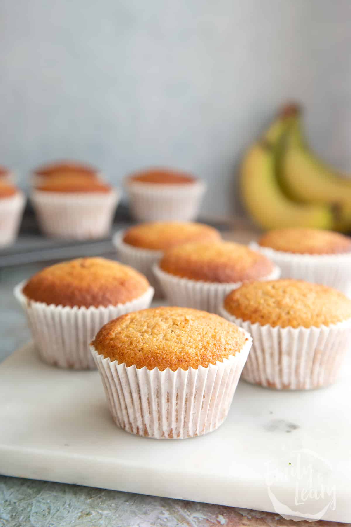 Banana cornmeal muffins on a white marble board. 