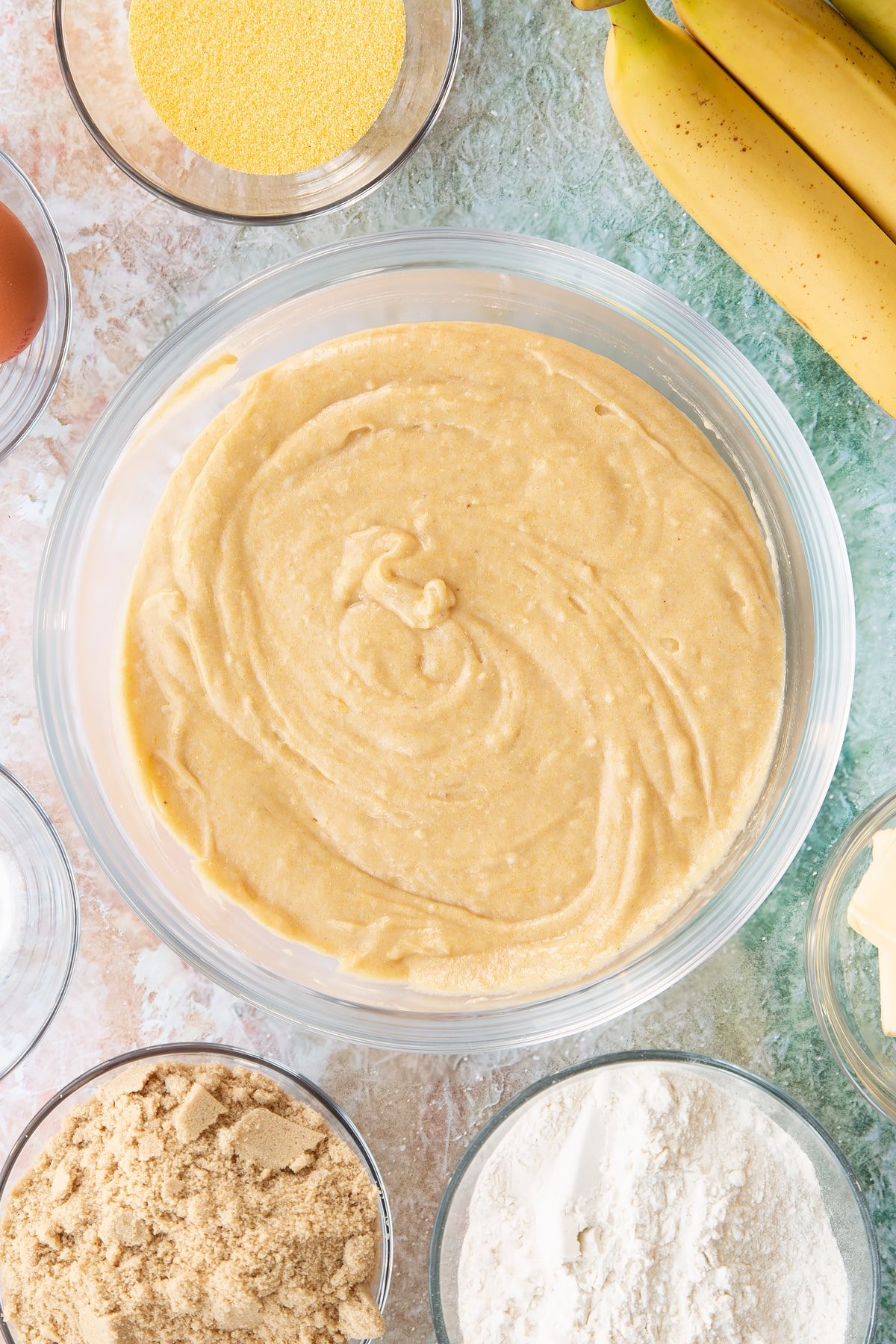 Banana cornmeal muffin batter in a glass mixing bowl.