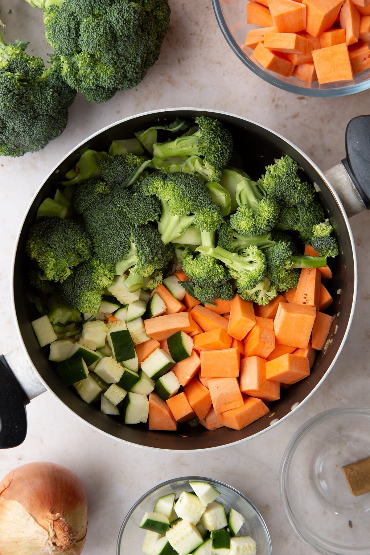 Overhead shot of some of the ingredients for the broccoli and sweet potato soup being added to the pan.