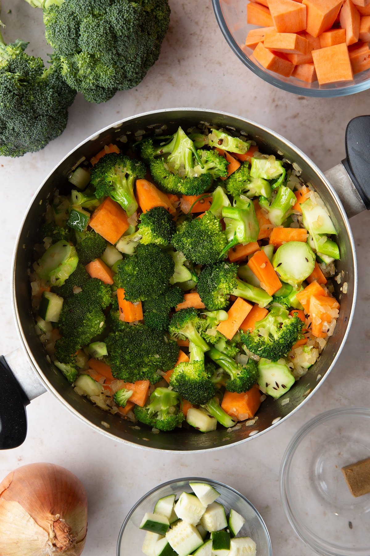 Overhead shot of the broccoli and sweet potato soup ingredients having been roasting in a pan for a couple of minutes. 