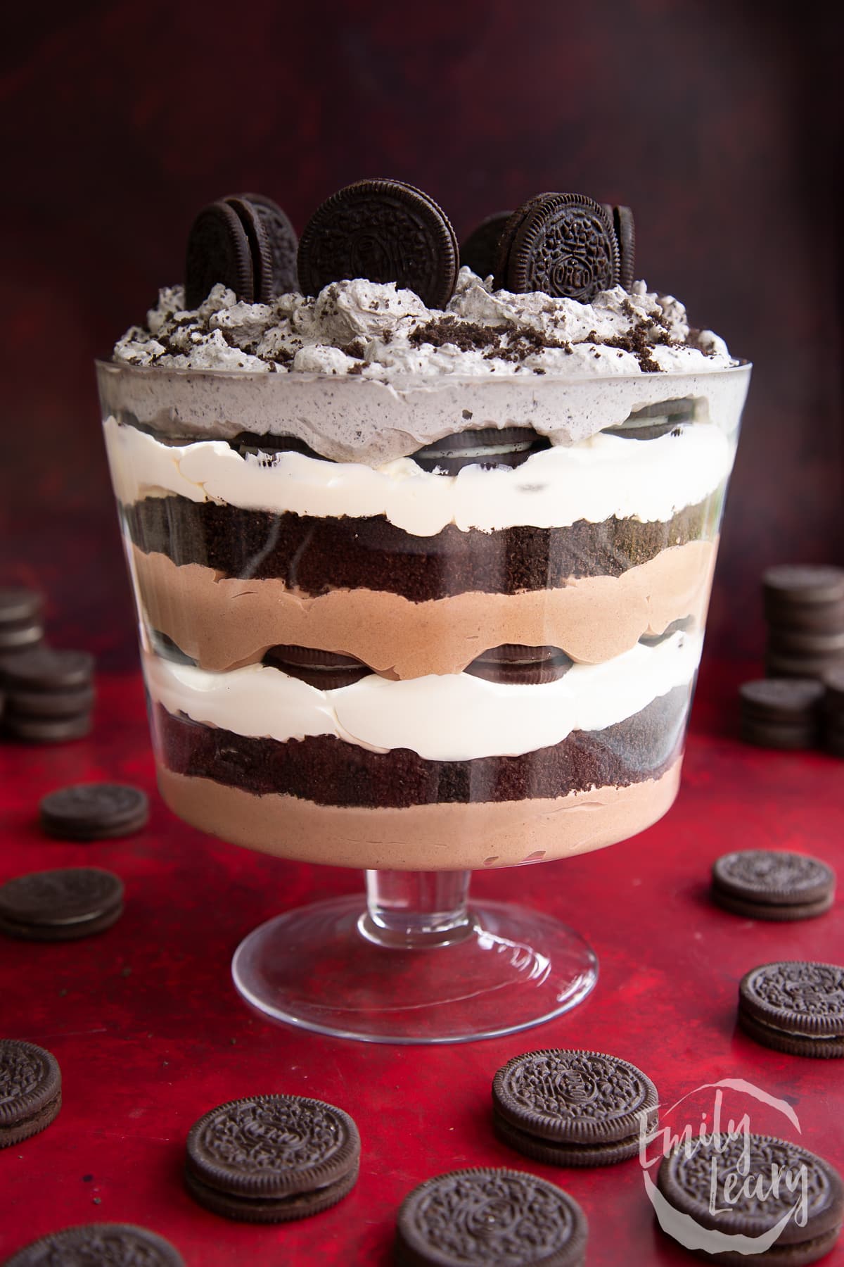Oreo trifle with layers of chocolate pudding, whipped cream and Oreos. Oreos stand on the top and it's finished with a sprinkling of crushed Oreos.
