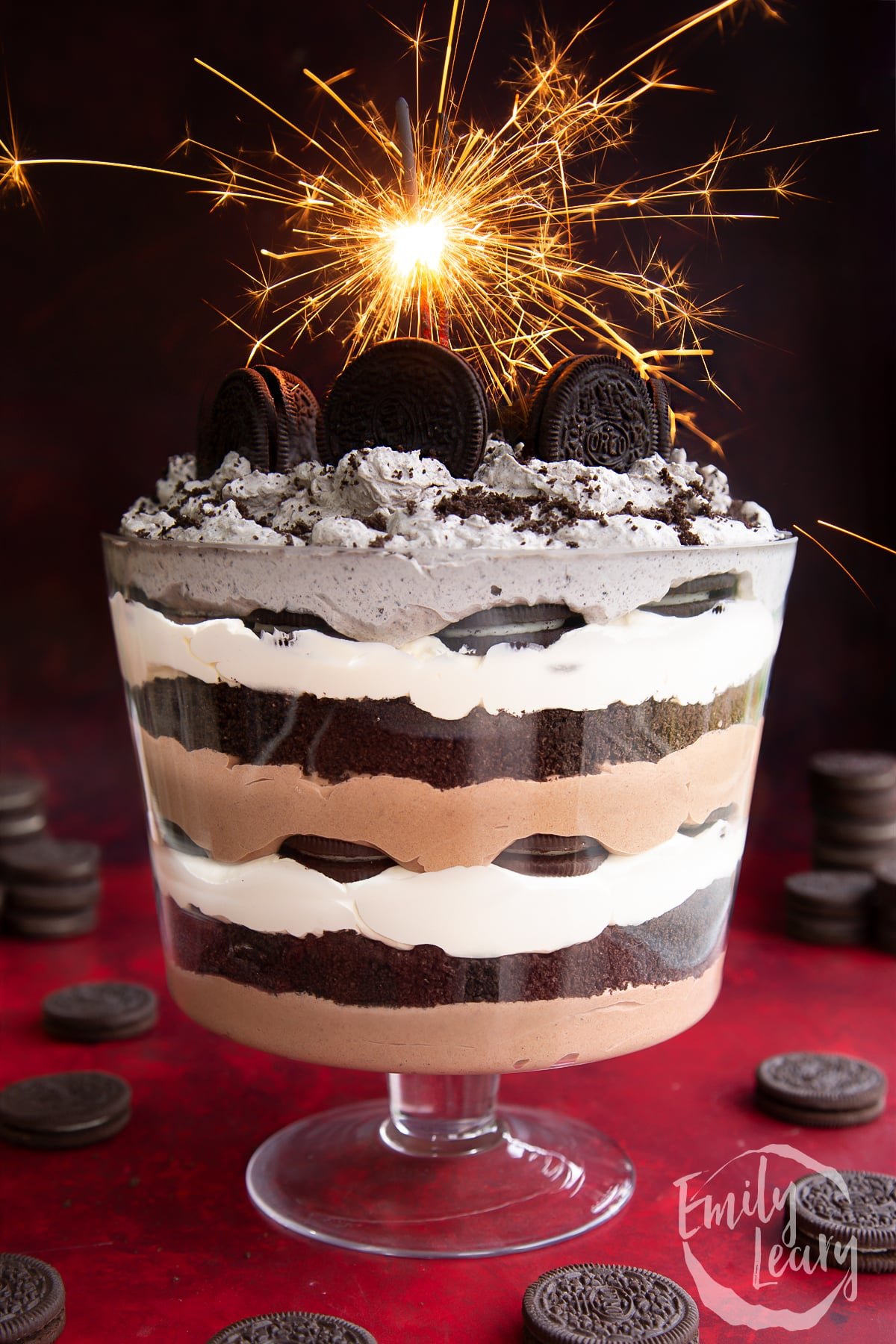 Oreo trifle with layers of chocolate pudding, whipped cream and Oreos. It's decorated with a sparkler.