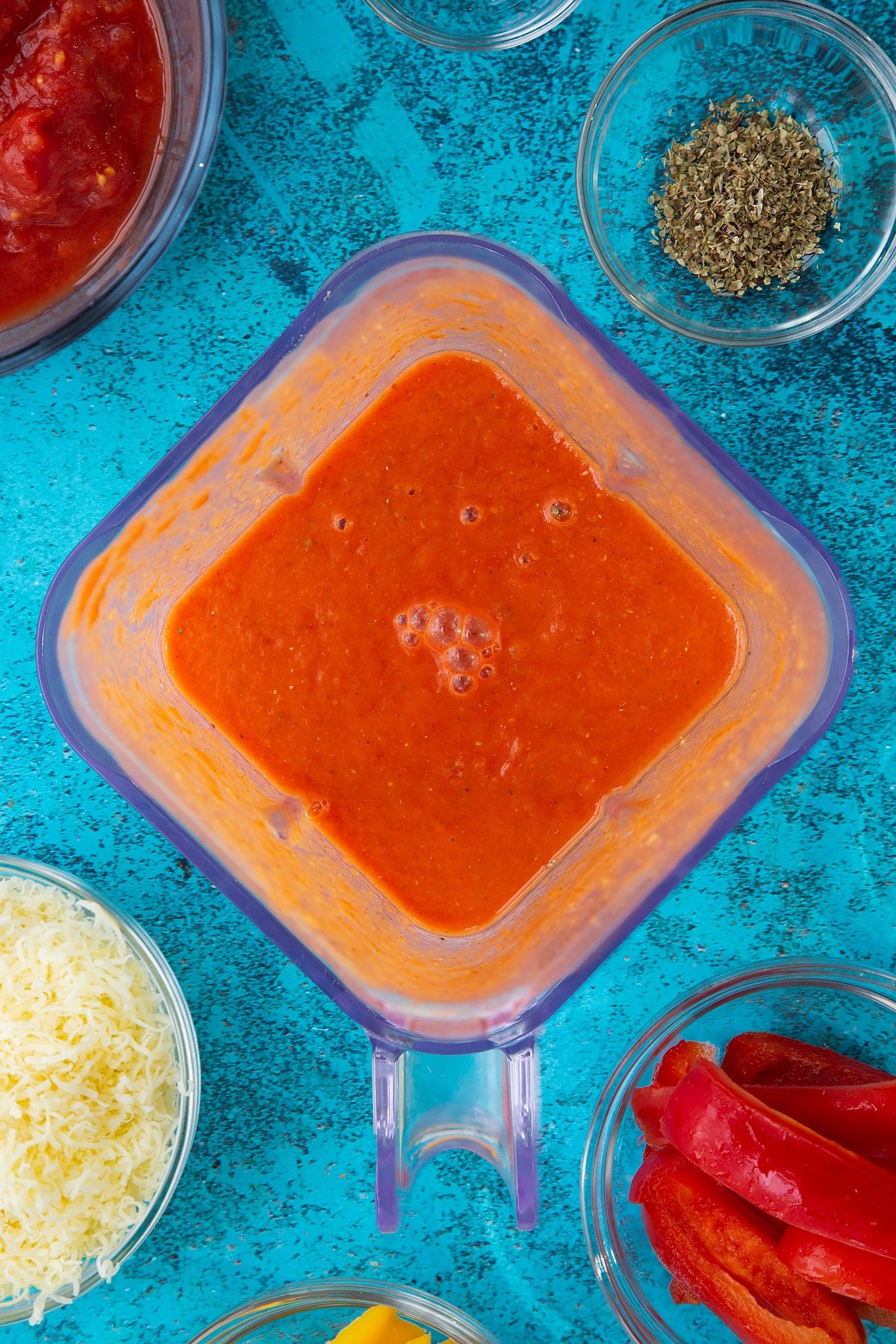 Enchilada sauce in a blender. Ingredients to make Quorn mince enchiladas surround the blender.