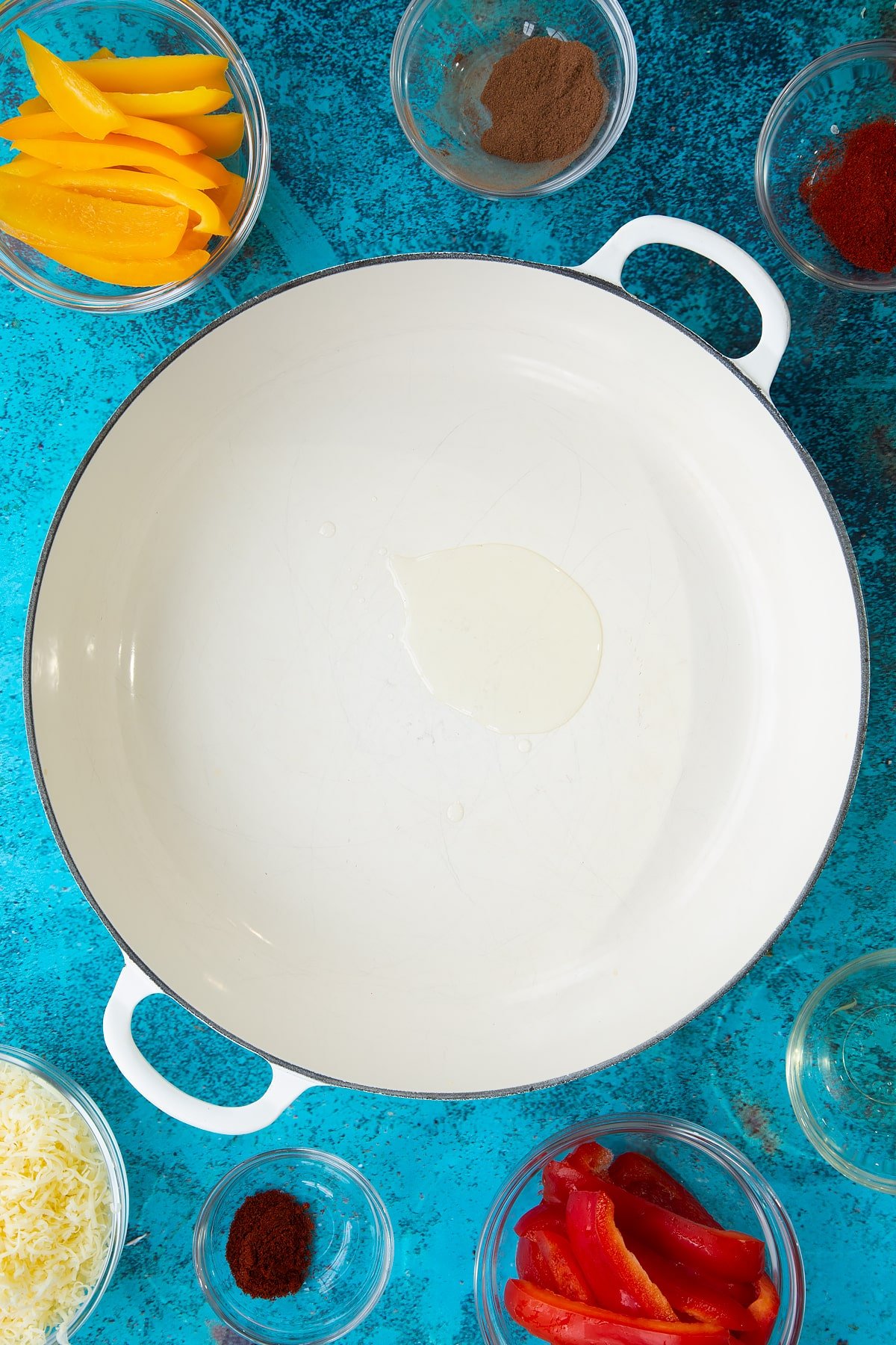 Oil in a large white pan. Ingredients to make Quorn mince enchiladas surround the pan.