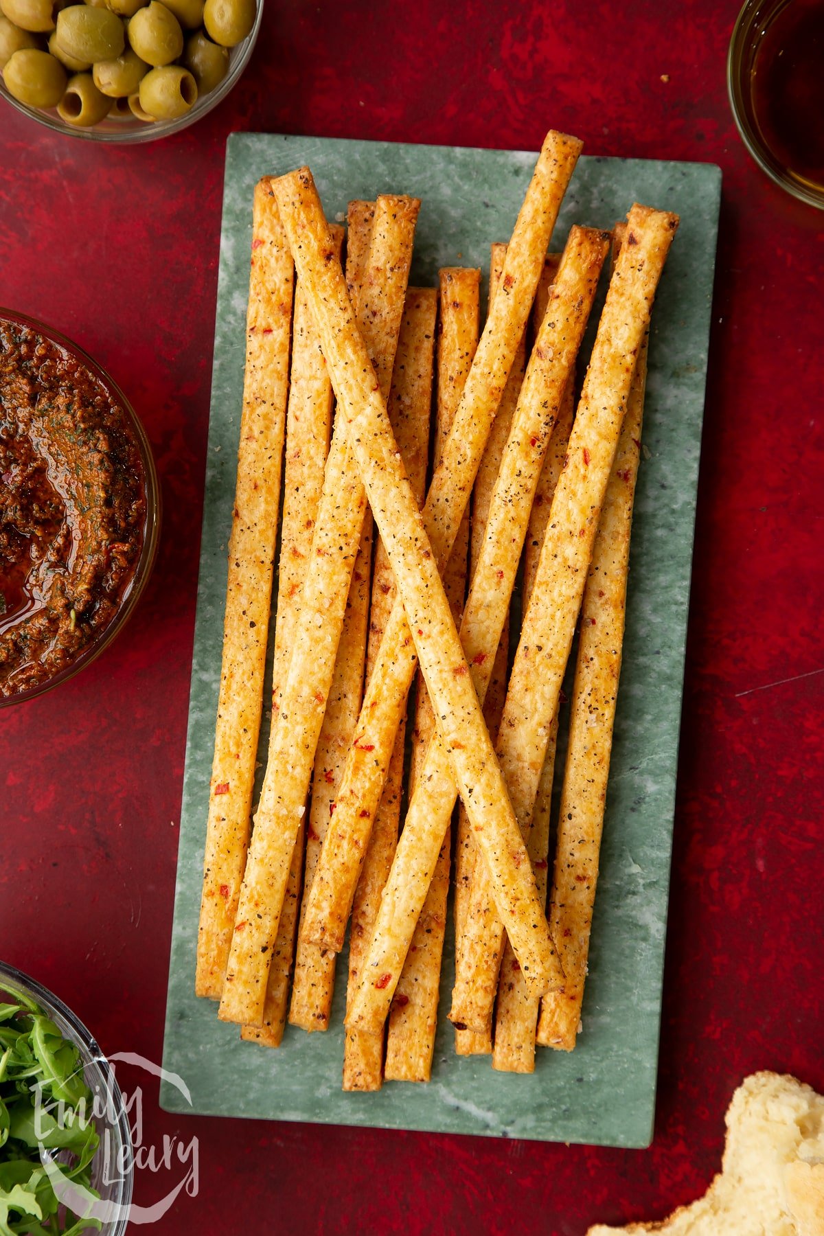 Overhead shot of the finished spicy cheese straws on a decorative serving board.