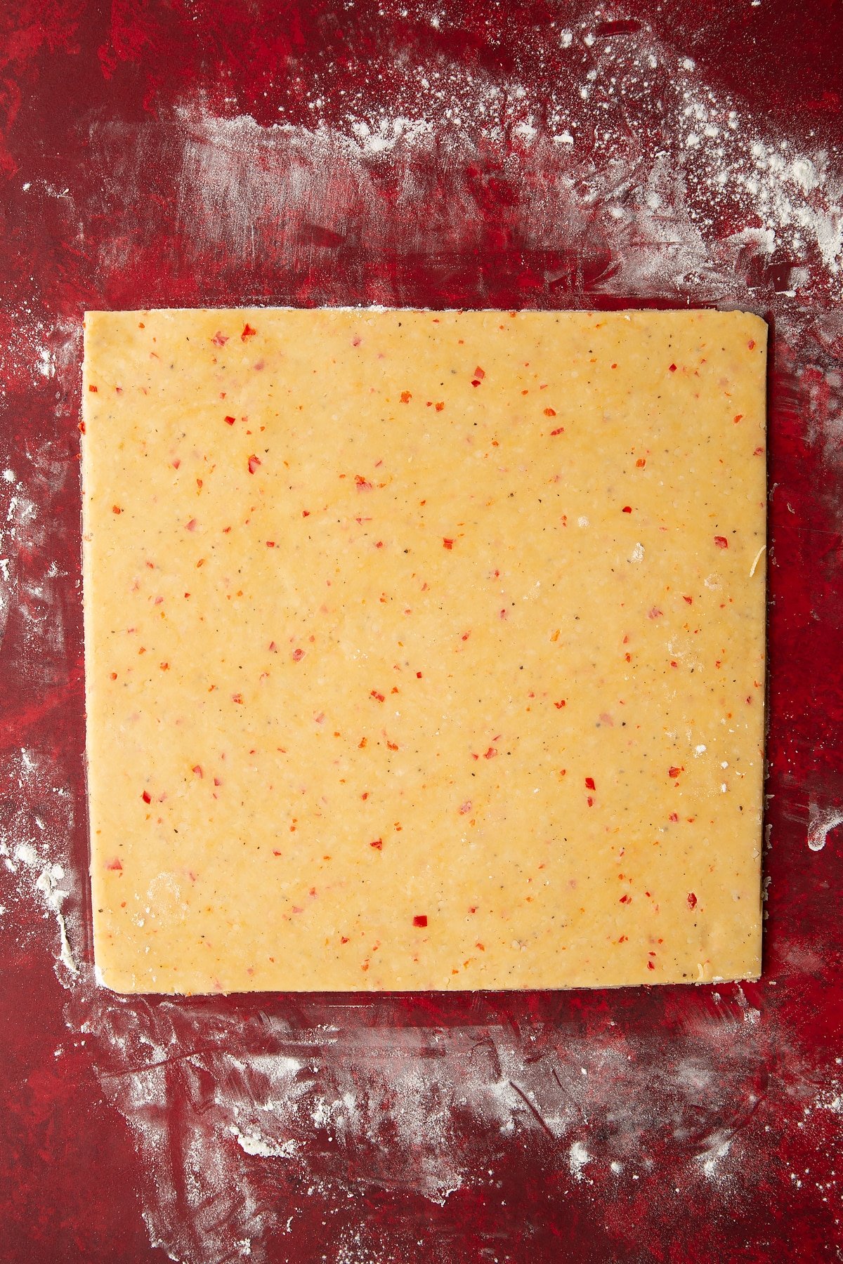 Overhead shot of the spicy cheese straws dough with the edges cut off so it's a neat square.
