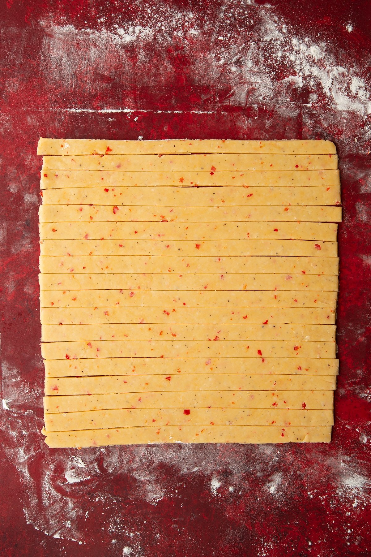 Overhead shot of the spicy cheese straws dough having been cut into long, thin slices.