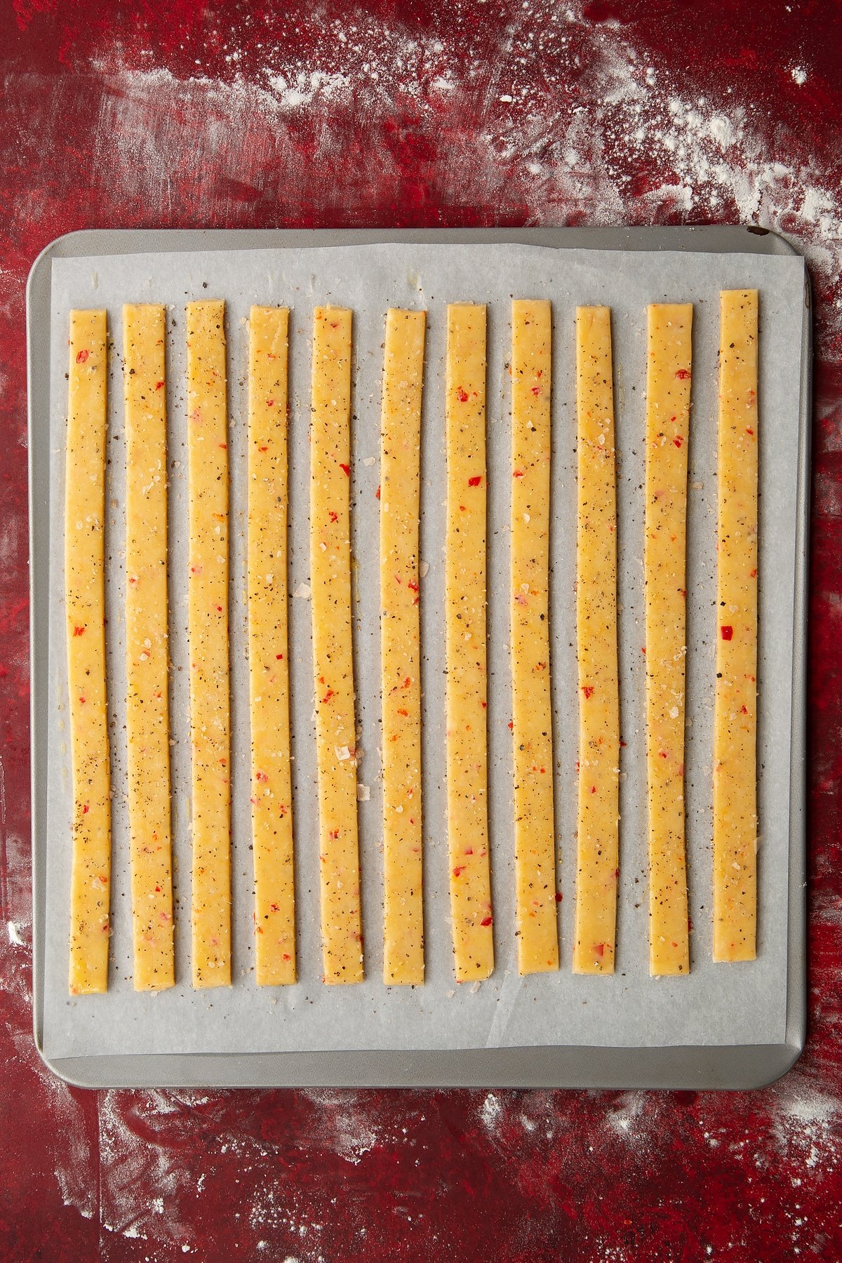 Overhead shot of the spicy cheese straws having been sprinkled with salt and pepper.