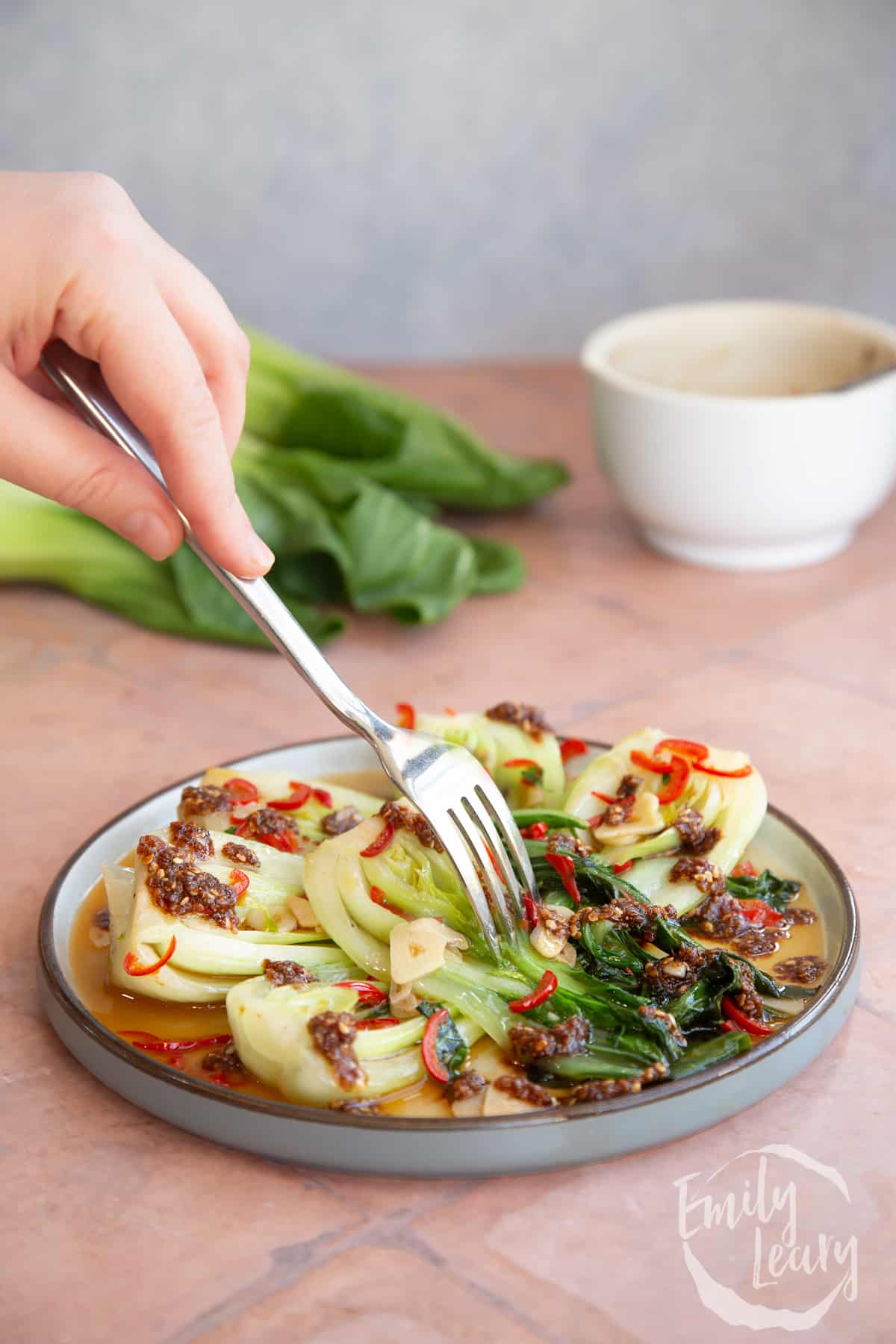 A plate of spicy pak choi recipe with a fork coming in from the top.