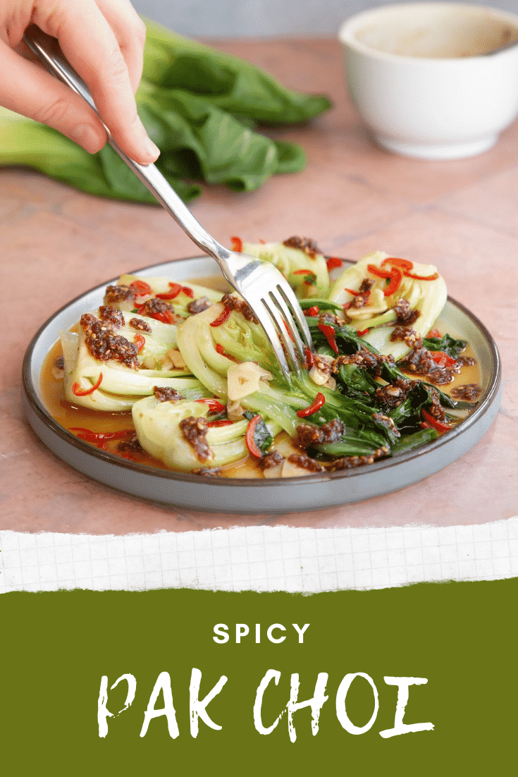 Spicy pak choi served on a plate with a fork coming in from the top with text at the bottom describing the image for Pinterest.