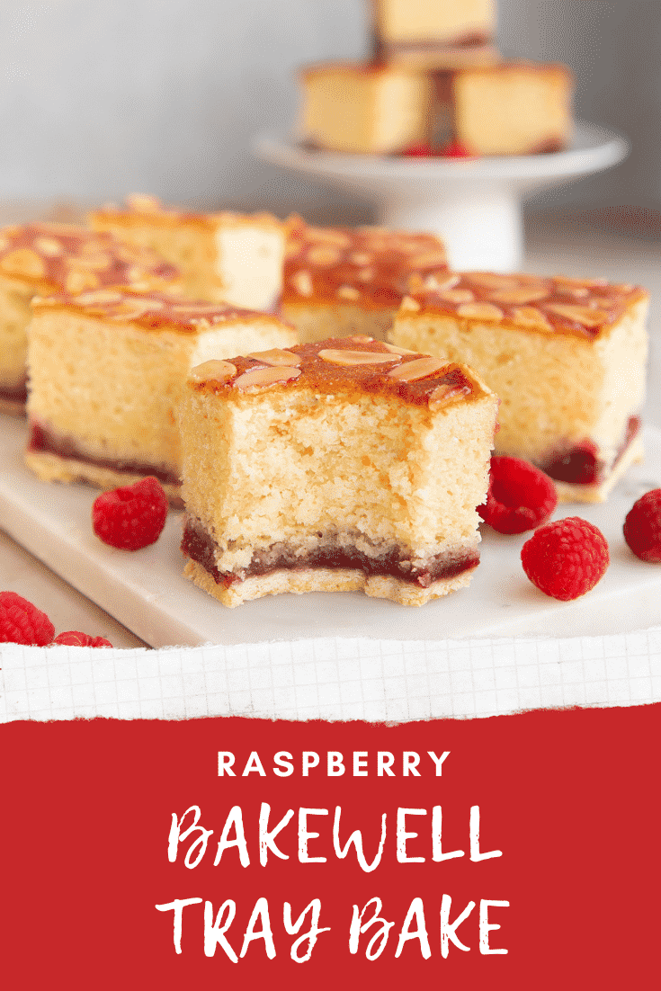 Squares of Bakewell tray bake on a white marble board. One has a bite out of it. Caption reads: Raspberry Bakewell tray bake.