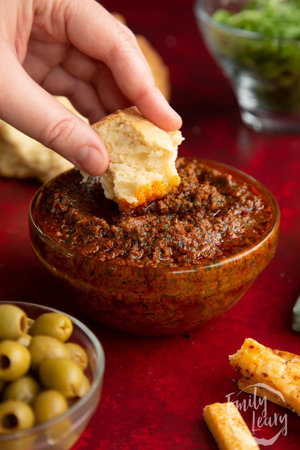 Finished chilli pesto with a slice of bread going into the dip from the top.