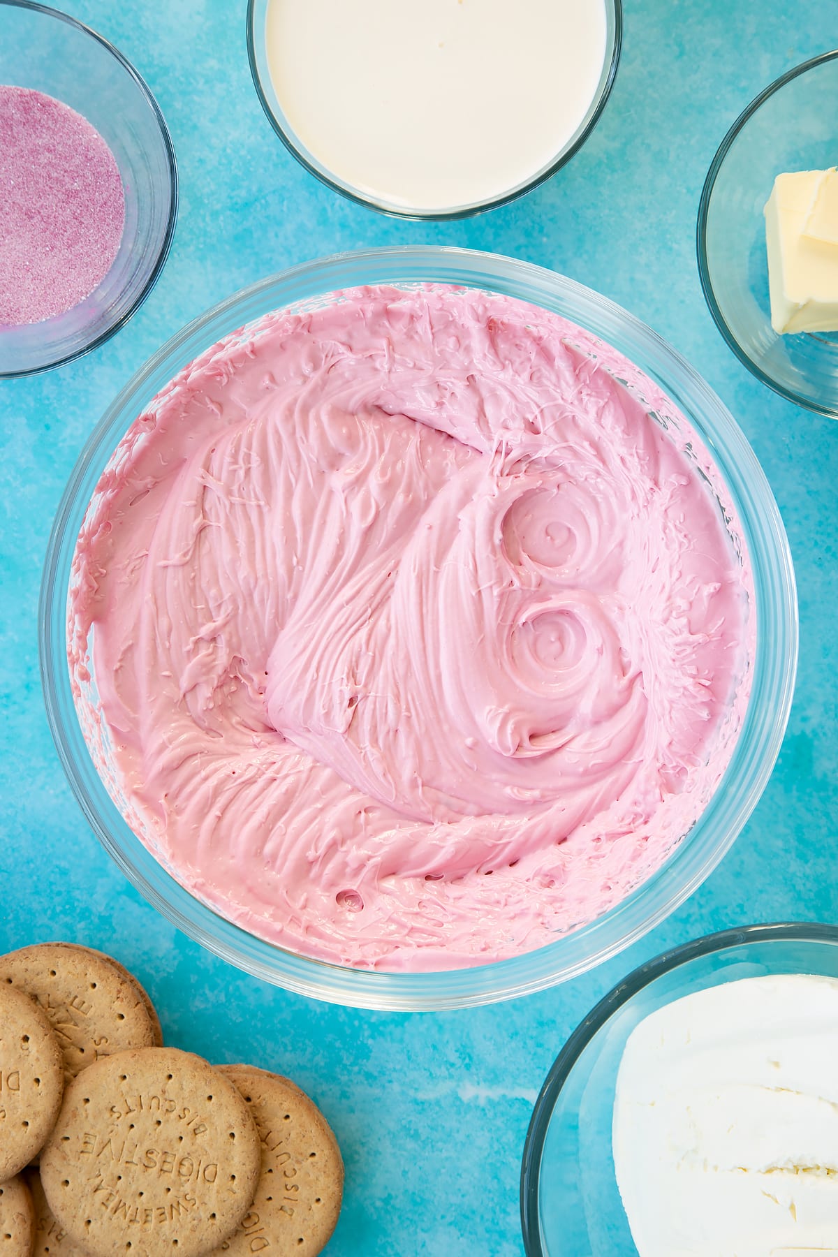 Pink jello cheesecake filling in a glass bowl.