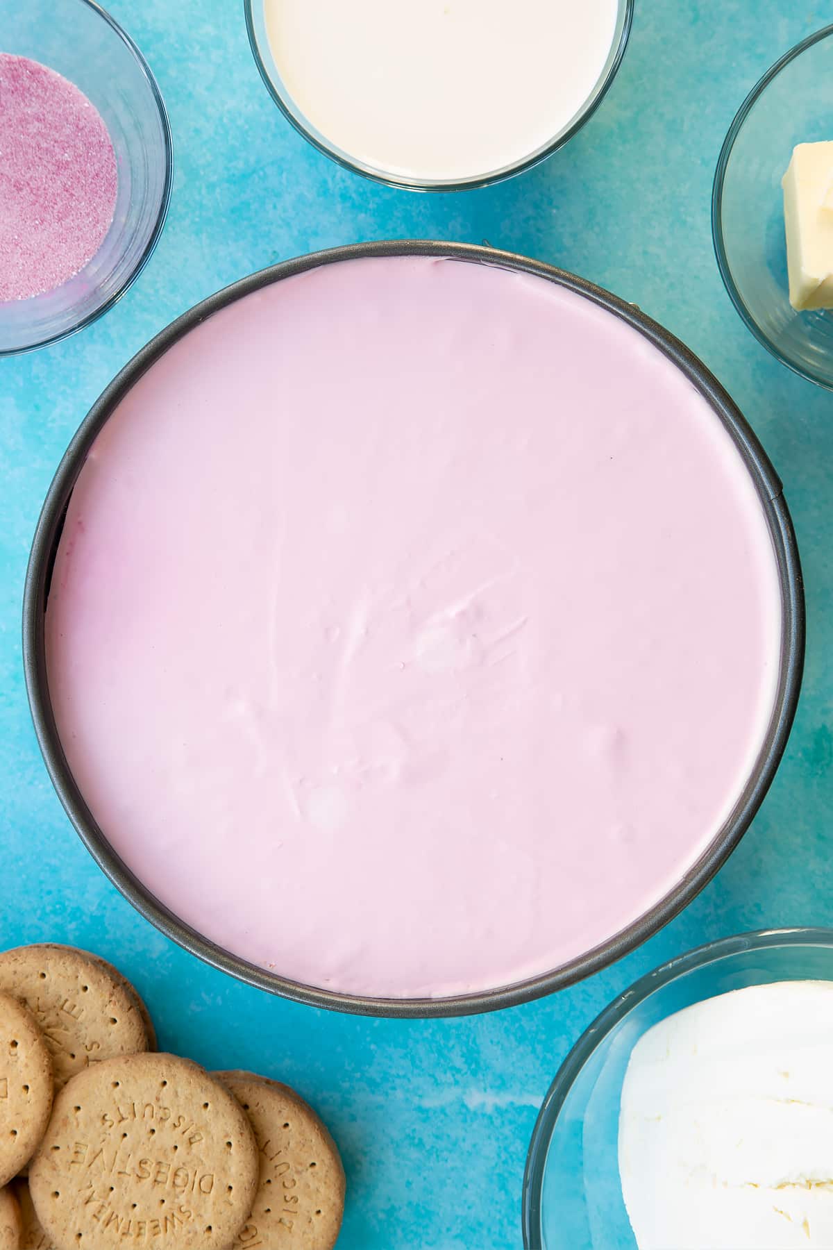 A pink jello cheesecake in a tin, shown from above.