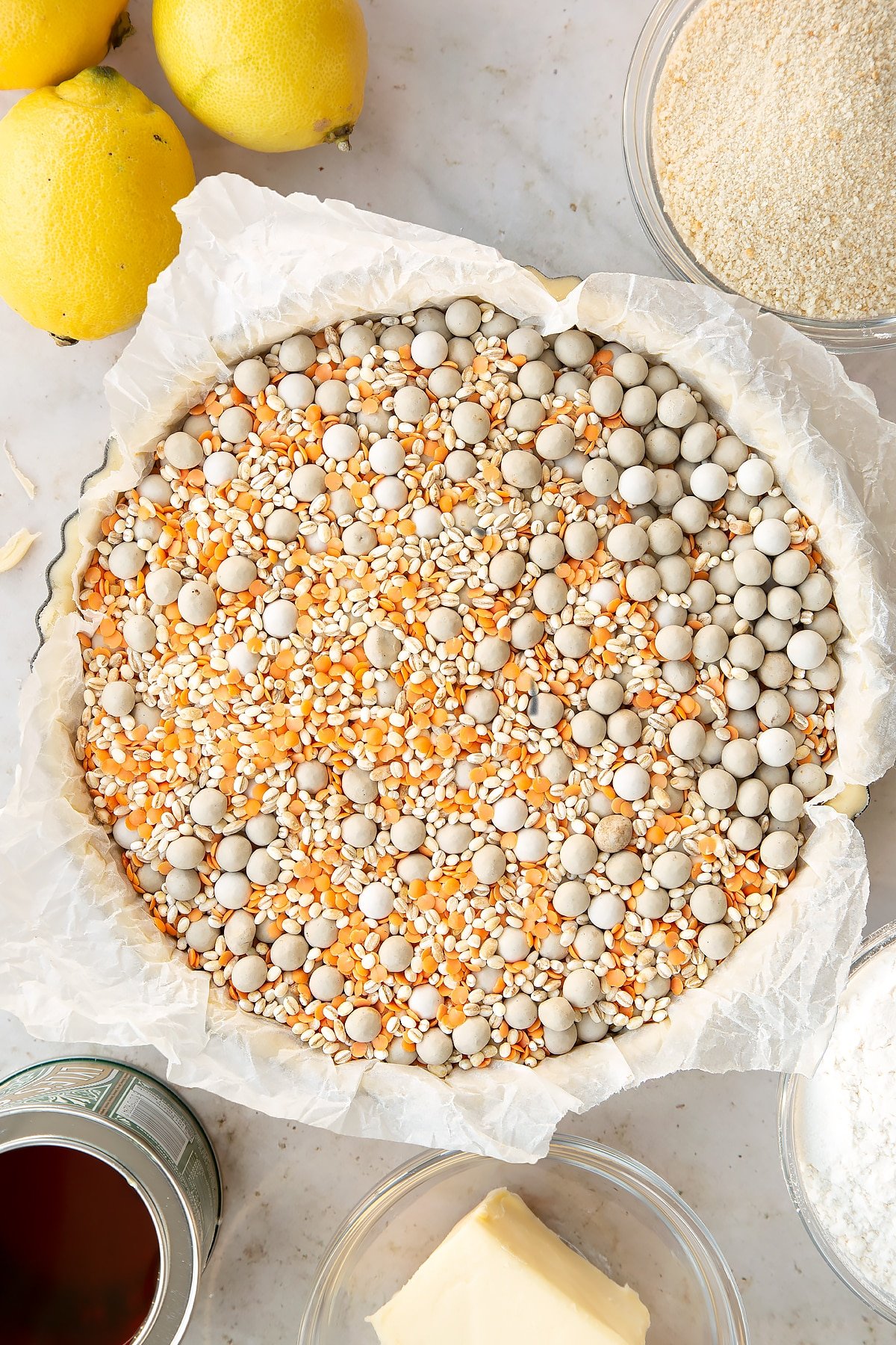 Overhead shot of the pastry tin having been lined with baking paper and baking beans.