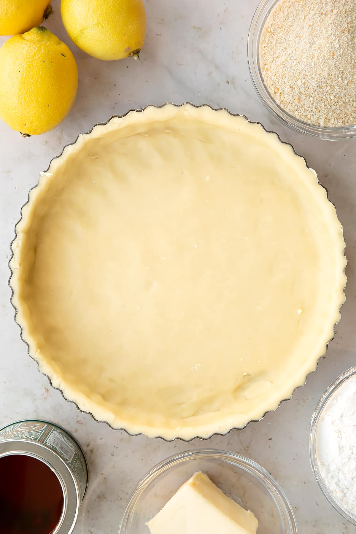 Overhead shot of the pastry tin lined with pastry having the edges been rolled off.