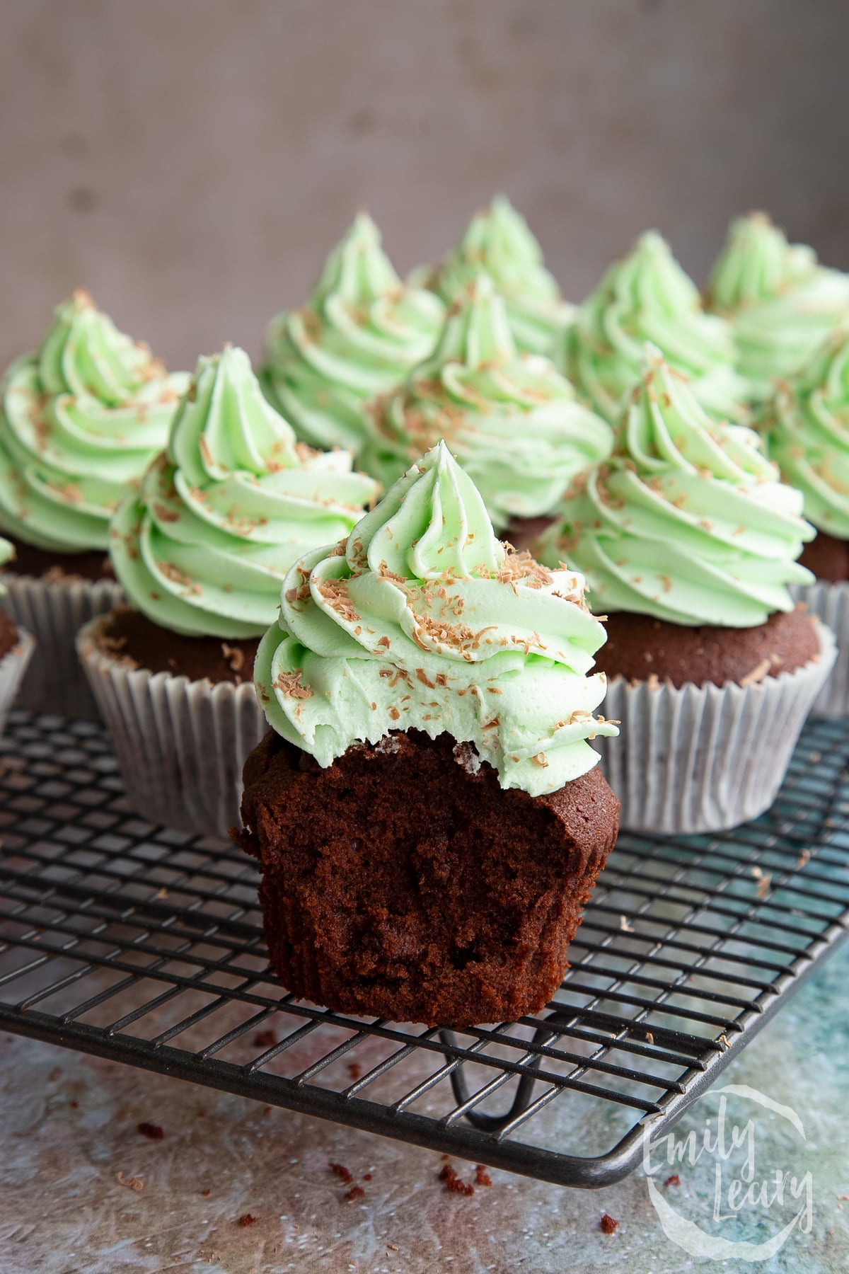 A mint choc chip cupcakes side on with a bite out of it.
