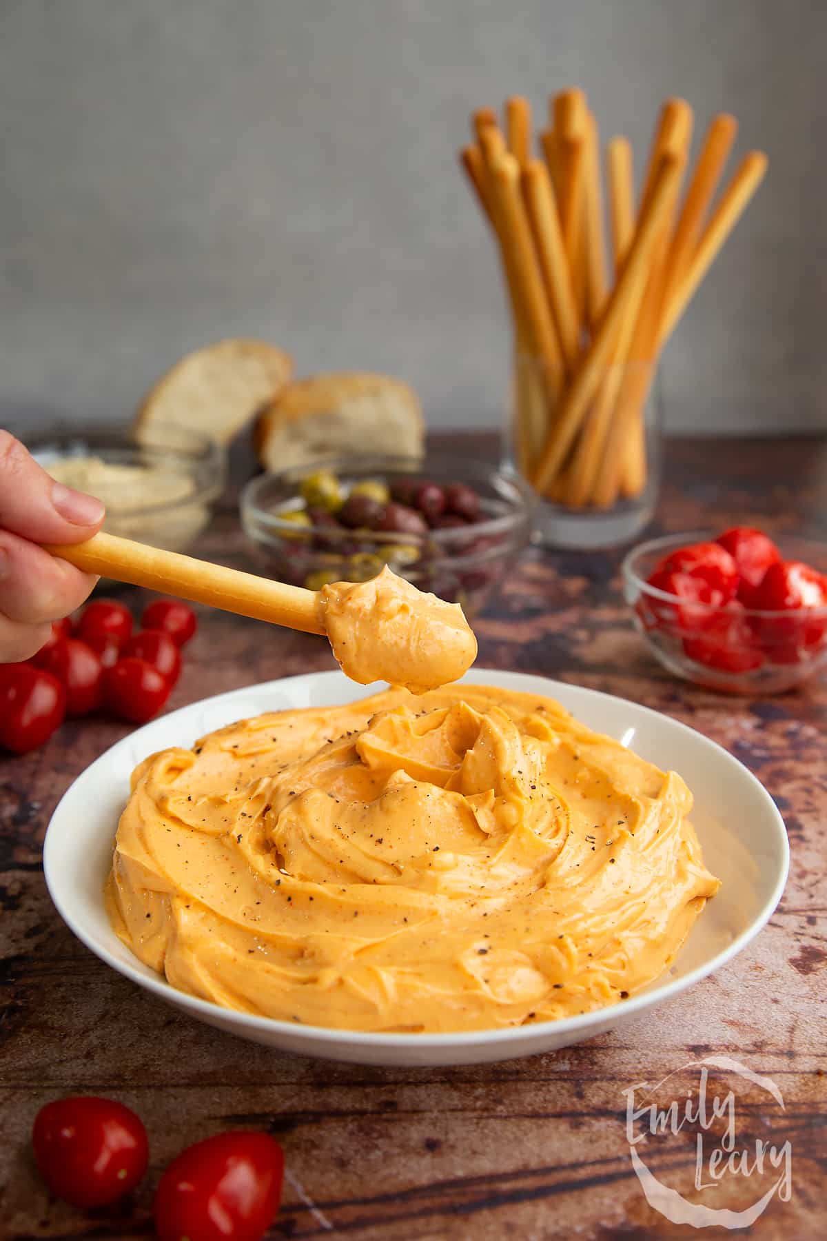 Paprika mayo in a shallow white bowl. A hand dips a breadstick into the mayo.