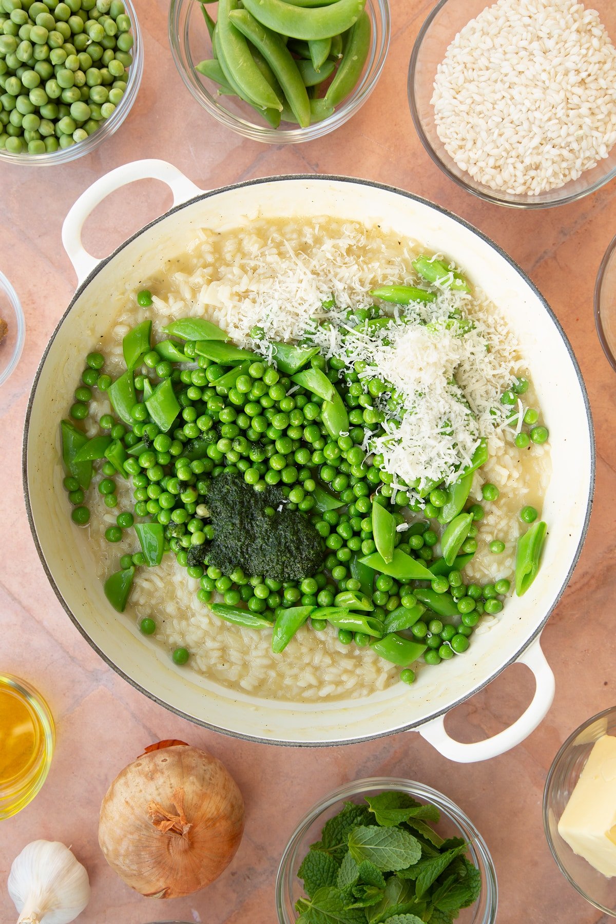 Overhead shot of the peas, mint paste and cheese being added to the pan of ingredients.