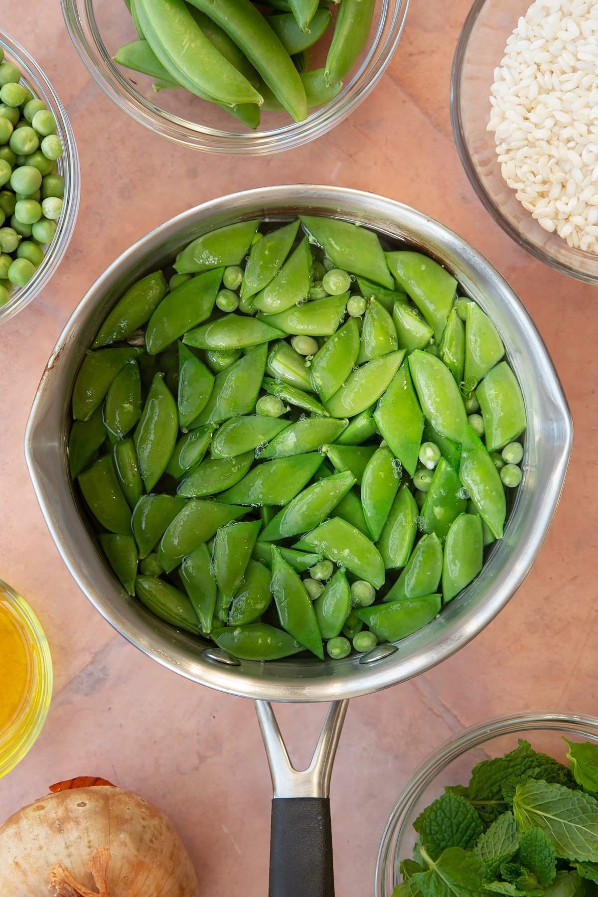 Overhead shot of peas in a pan with water.