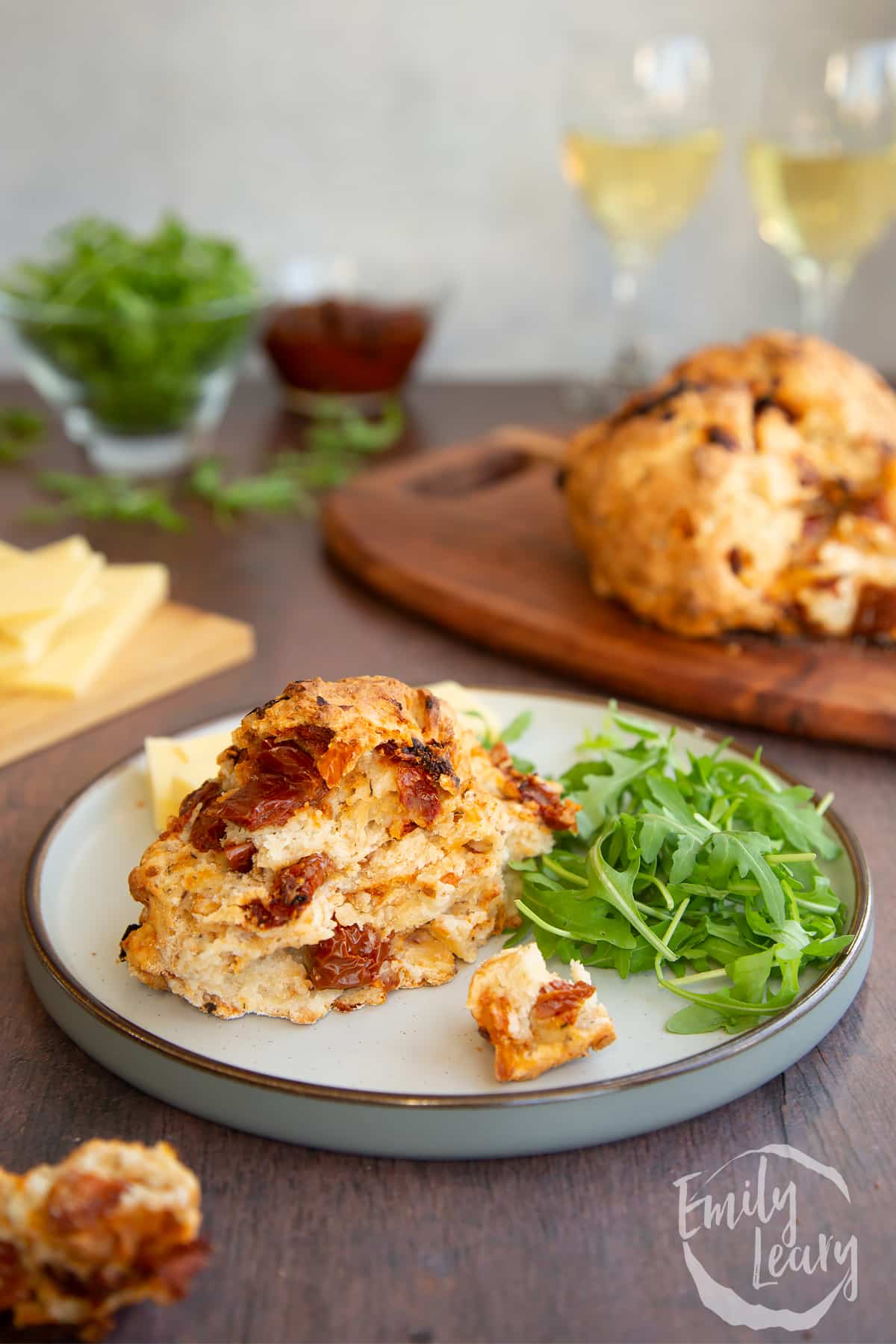 A piece of Sundried tomato soda bread on a grey plate with some rocket and cheese.