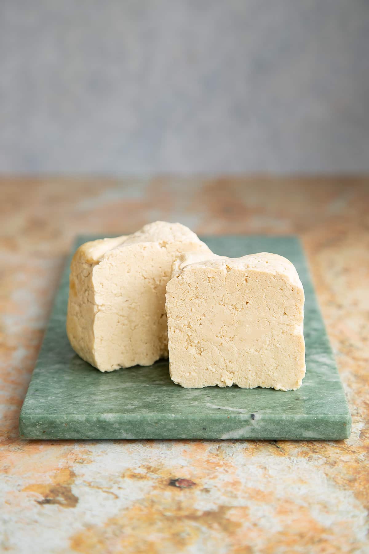 a block of steamed tofu on a green marble board bu tin half.