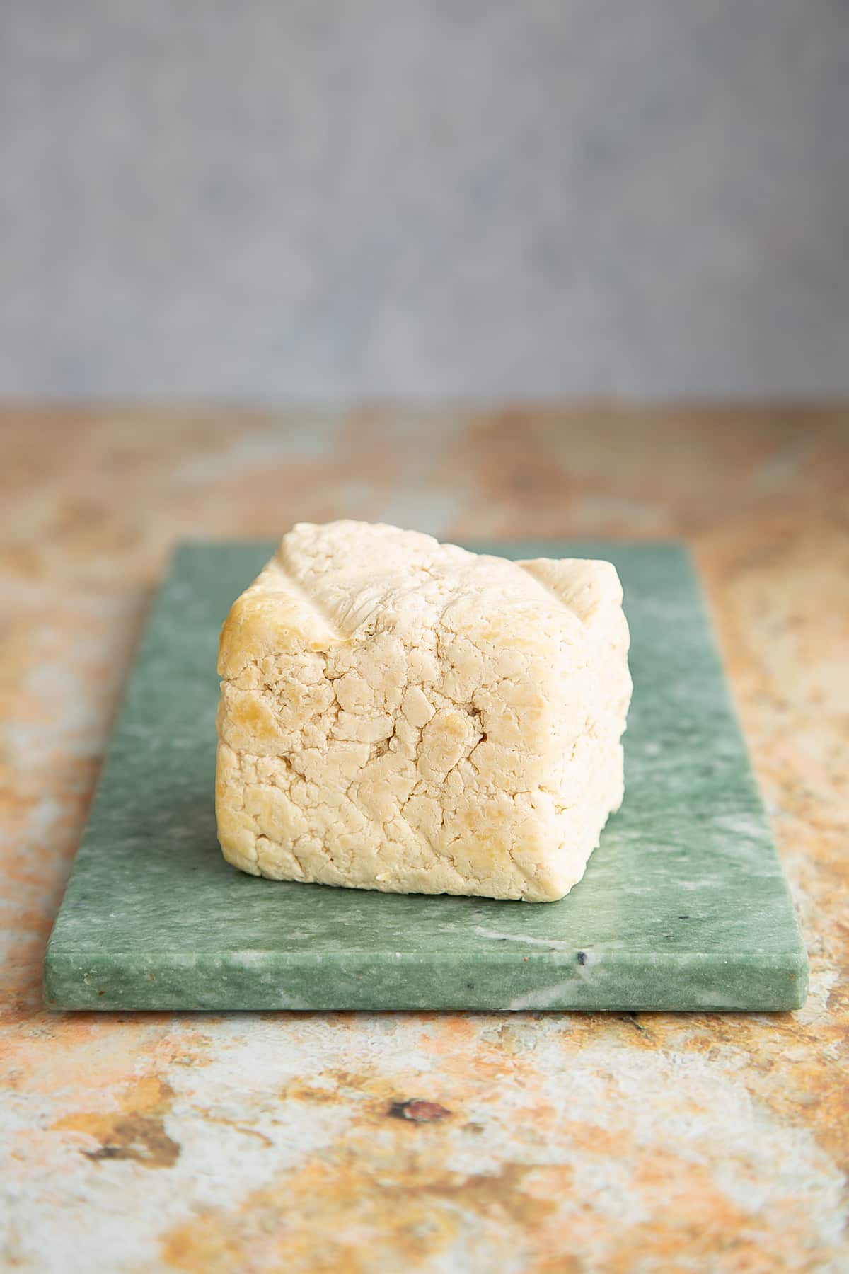 a block of steamed tofu on a green marble board.