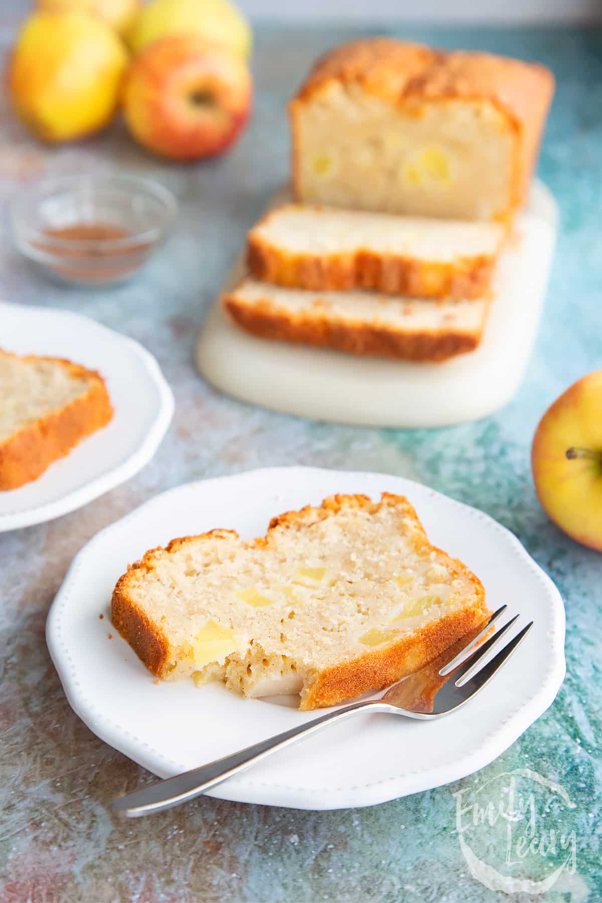 Sliced gluten free spiced apple cake served on a white plate with a decorative fork on the side. 