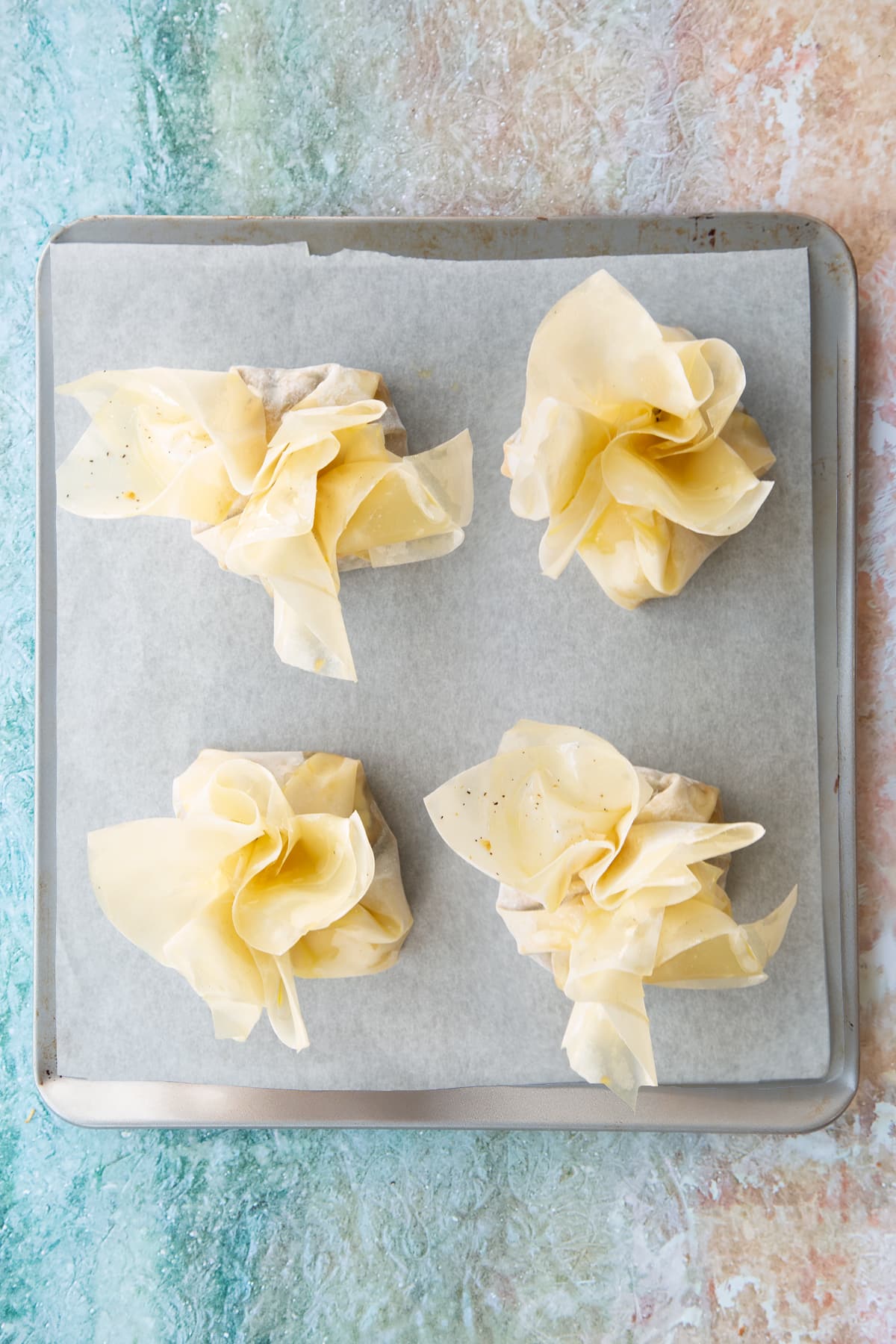 4 Ruffled filo pastry drizzled with oil placed on a greaseproof lined baking tray.