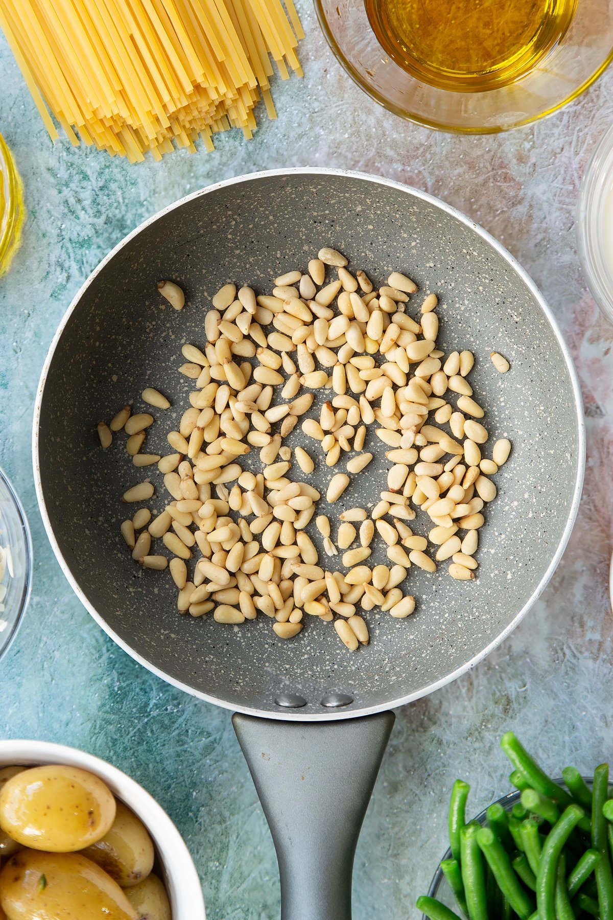 Overhead shot of the pine nuts in a pan being toasted.