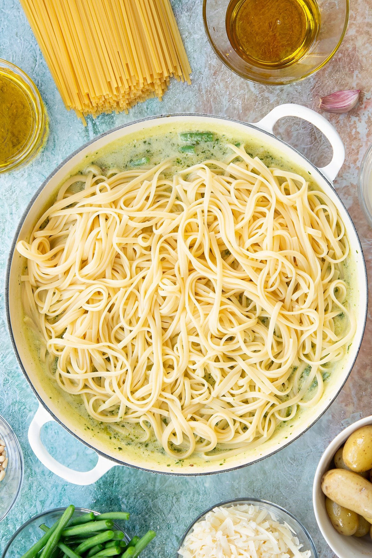 Adding the pasta to the Linguine alla genovese ingredients in a pan.