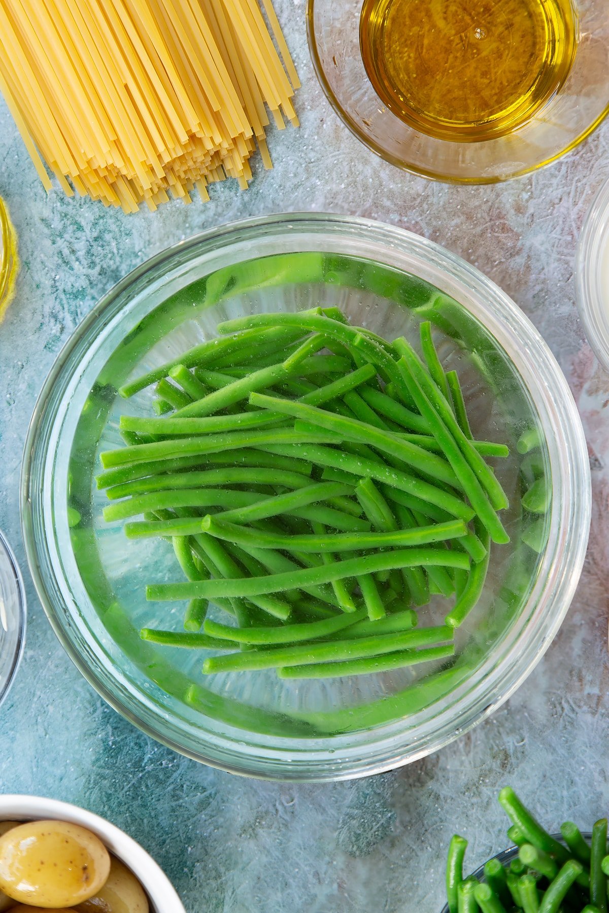 Overhead shot of green beans in a bowl with water.