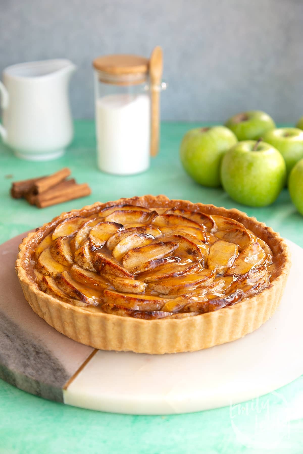 Side on shot of the finished apple custard tart served on a decorative board.