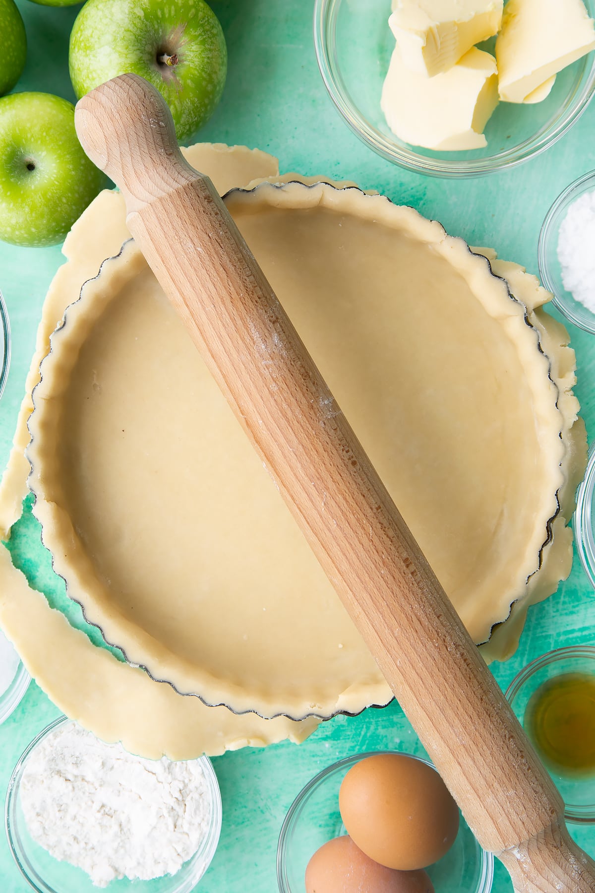 Trimming the edges off the pastry on the pastry tin by rolling a rolling pin across the top.