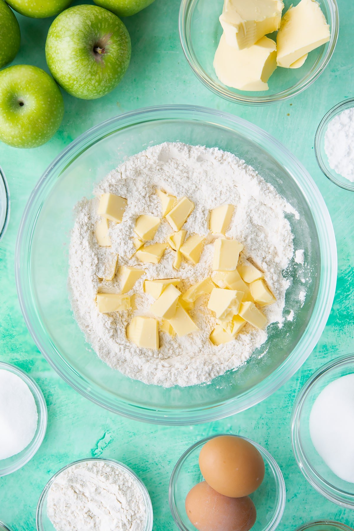 Adding butter to the bowl of icing sugar and flour.