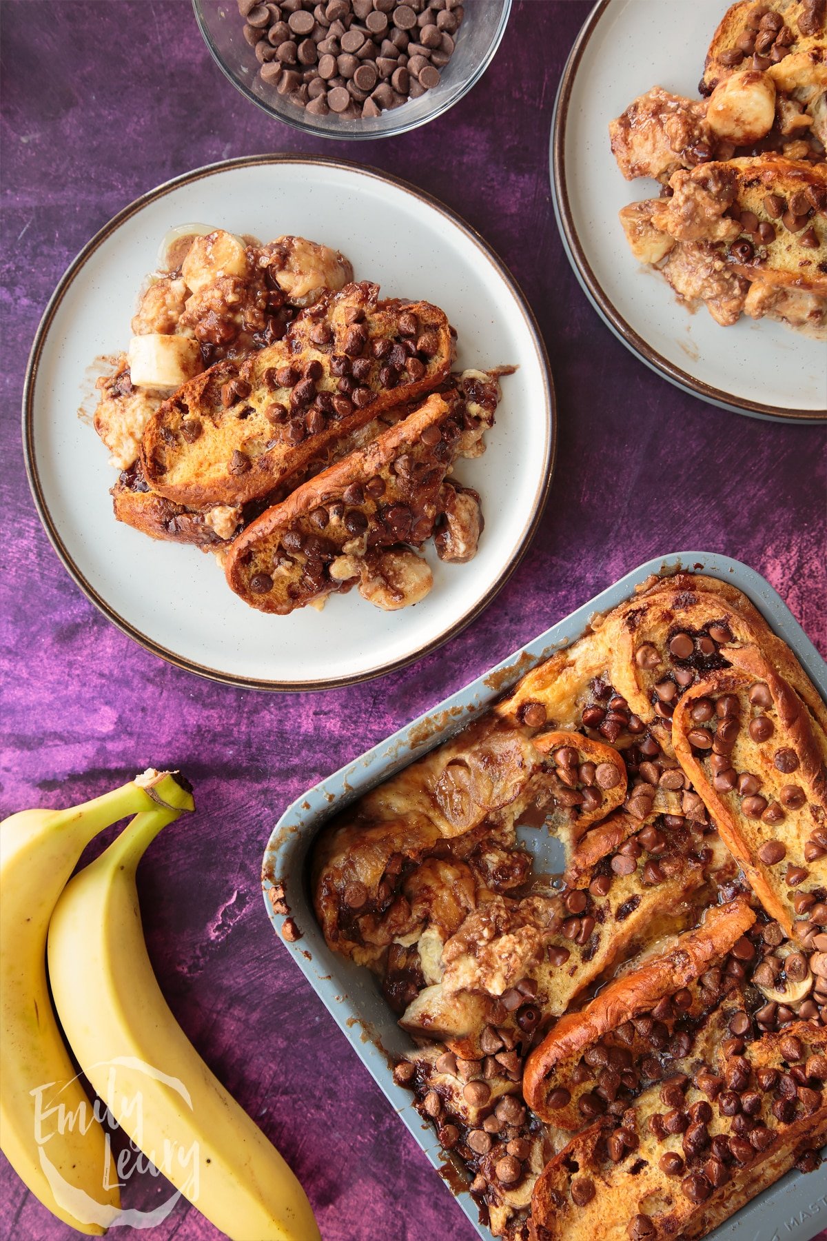 Overhead shot of chocolate banana bread pudding served on a decorative plate with the finished pan of chocolate banana bread pudding on the side.